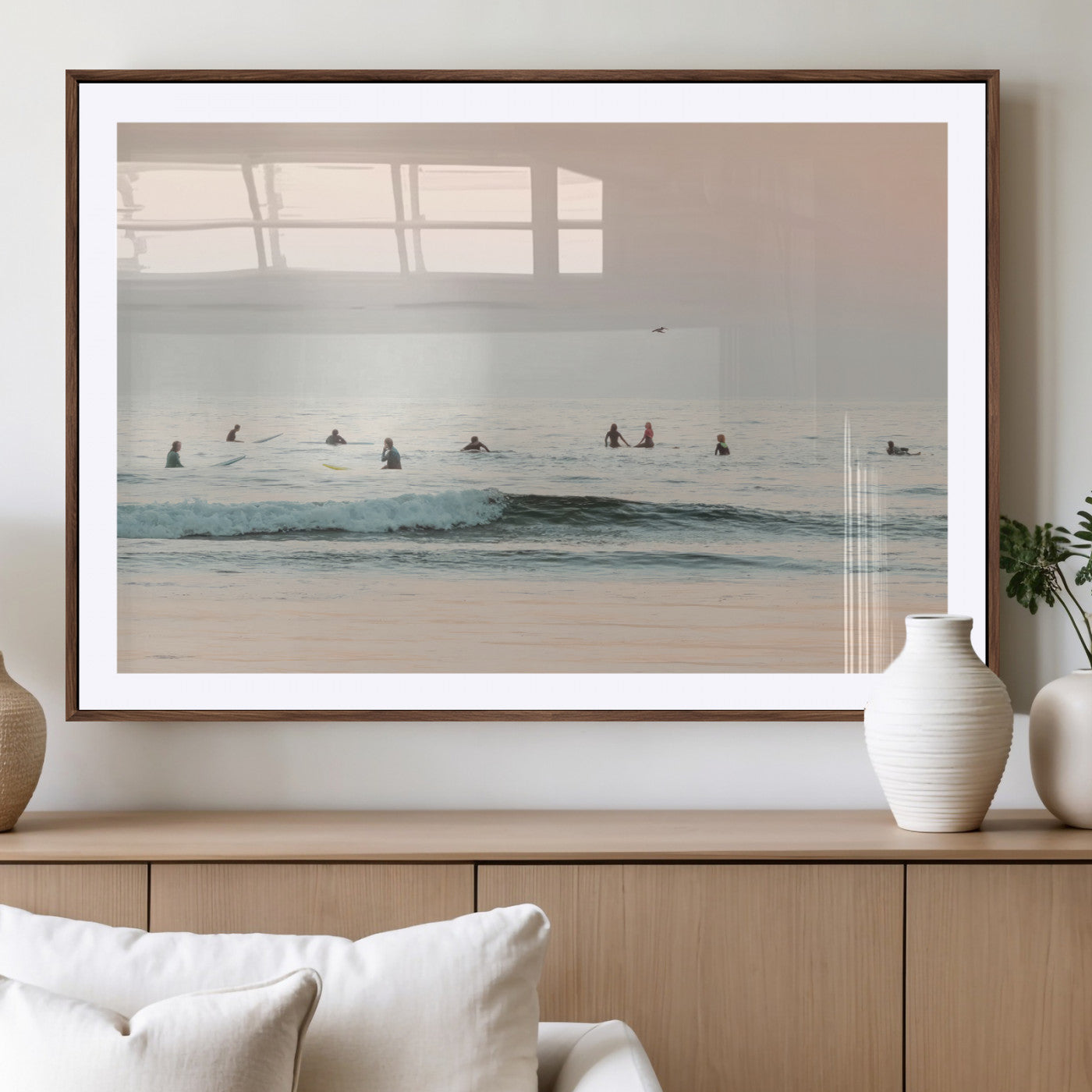 Dreamy photo of surfers waiting on soft pastel waves under a pink sunset sky, ideal for soft coastal minimalist or serene ocean-themed home decor.