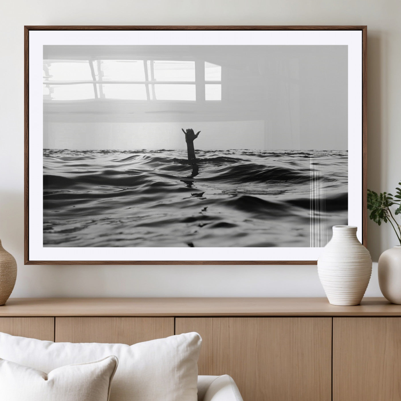 Black and white ocean with a hand making a surfer sign among dark waves, creating a dramatic and minimalist seascape with bold contrast.