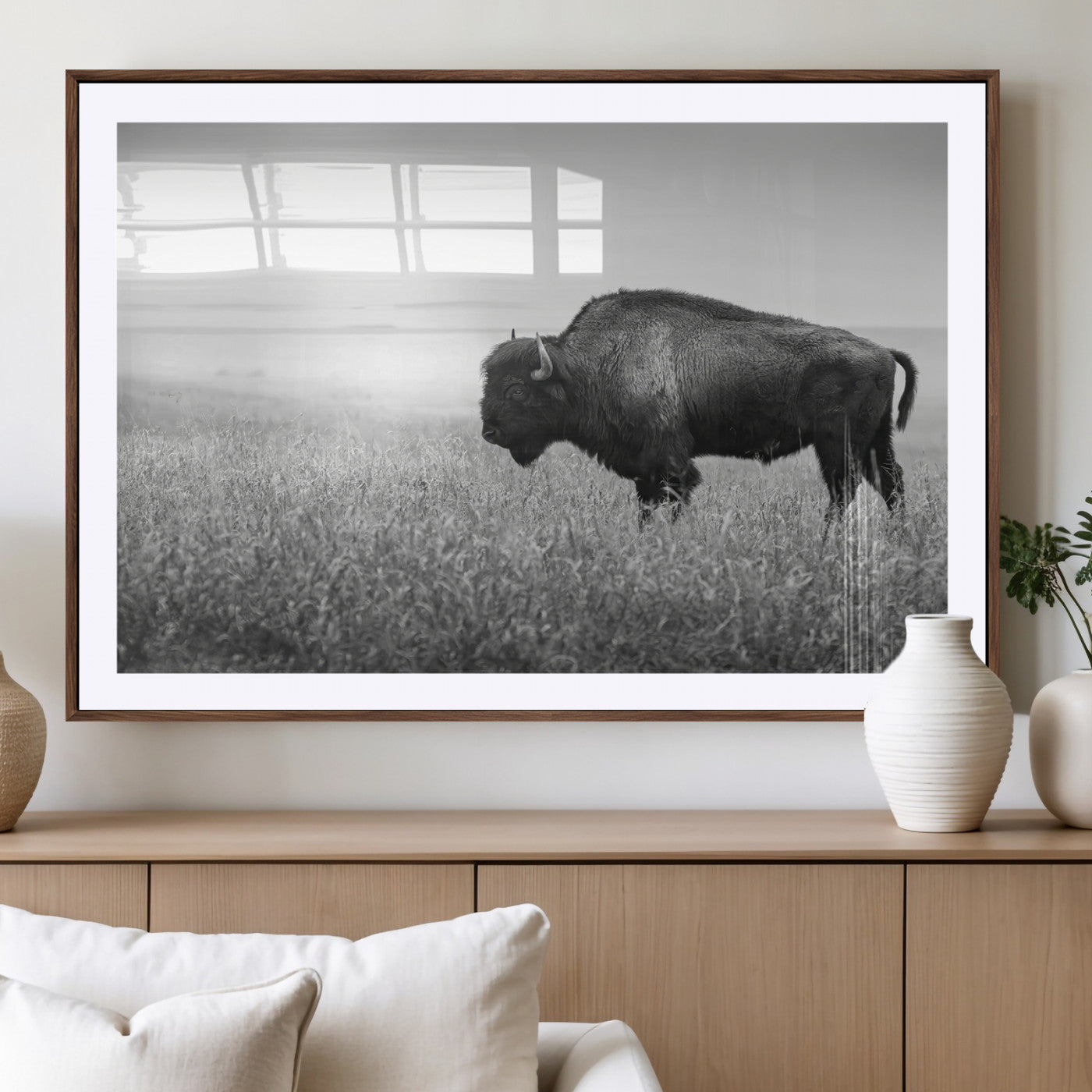A black and white photograph of a majestic bison standing in a vast grassy prairie, evoking a sense of wilderness and strength.