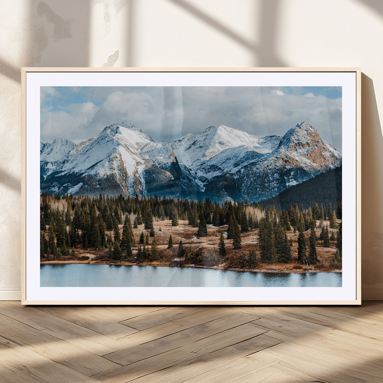 Framed canvas of snowy mountain peaks with pine forest and alpine lake, perfect for winter cabin or wilderness-inspired home decor.