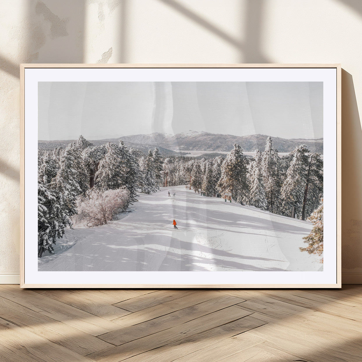 Bright ski trail lined with snow-covered pines and a skier in orange, perfect for alpine adventure or winter sports-inspired decor.