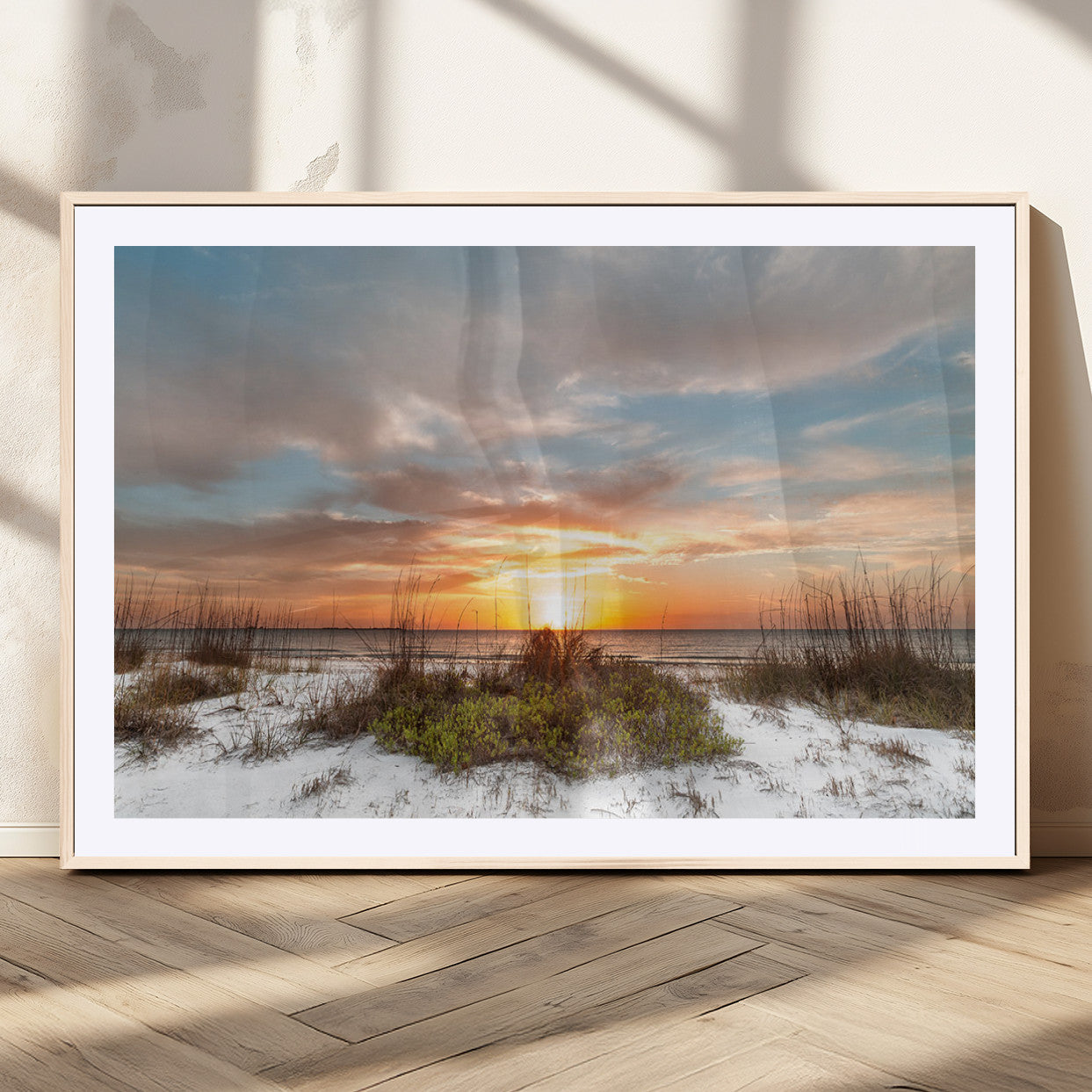A tranquil beach scene featuring golden sunset hues over the water, with grasses in the foreground and a peaceful, serene atmosphere.