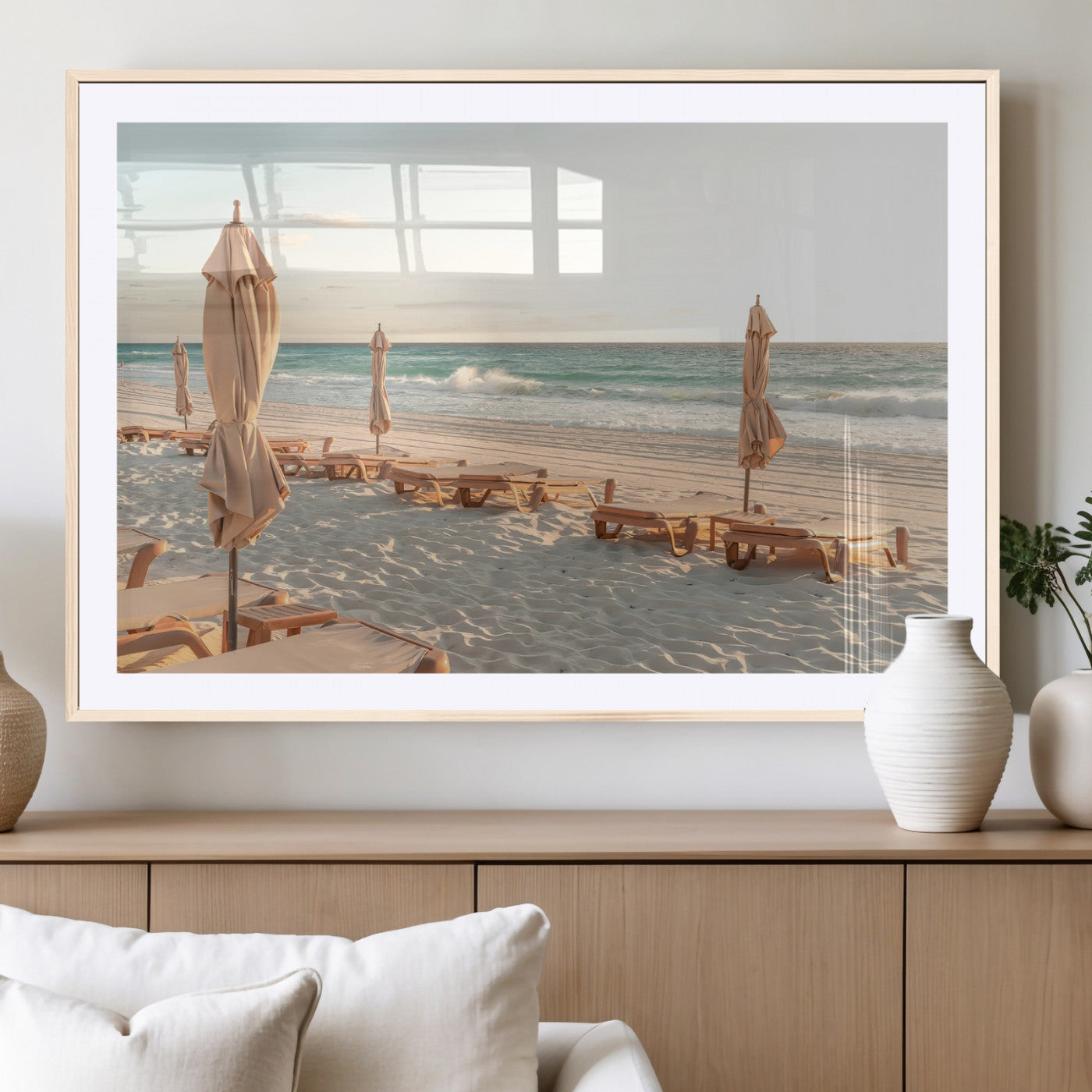 Minimalist photo of empty beach loungers and umbrellas on soft sand, ideal for calm seaside or pastel coastal-style home decor.