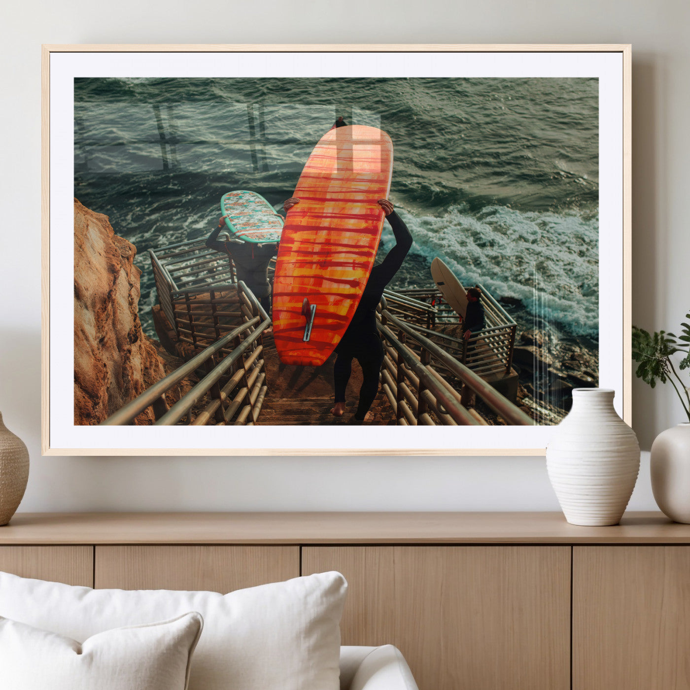 A surfer carrying a bold orange surfboard down a rugged staircase toward the ocean, bathed in golden hour light, capturing the energy of coastal adventure.