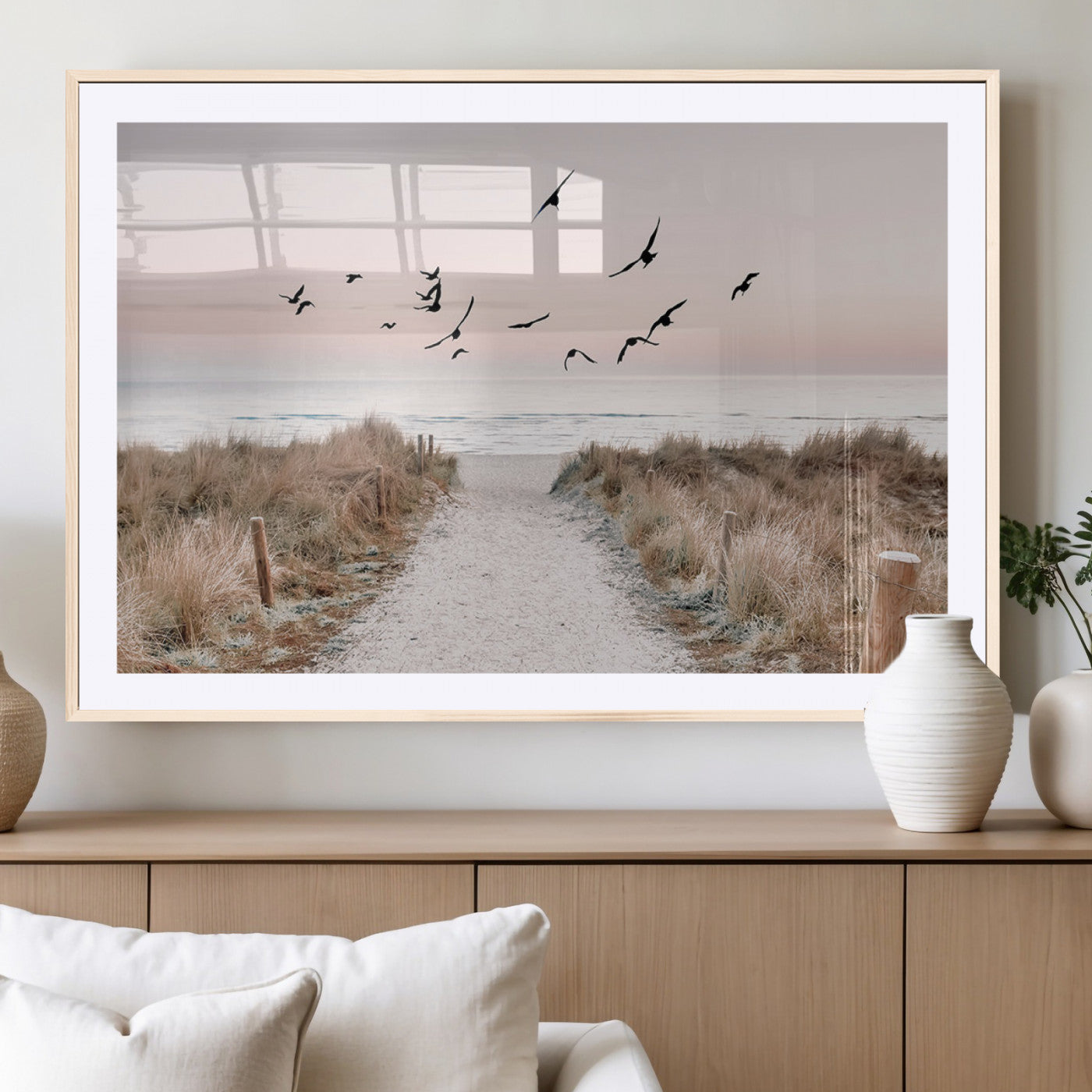 A peaceful coastal pathway leading to the ocean, with birds flying across a soft pastel sky, creating a calm and scenic beach atmosphere.