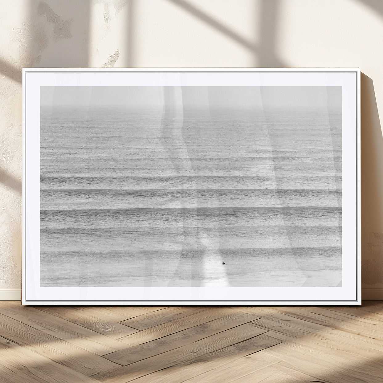 Monochrome photo of a lone surfer in calm layered waves, perfect for minimalist coastal or moody ocean-inspired wall decoration.