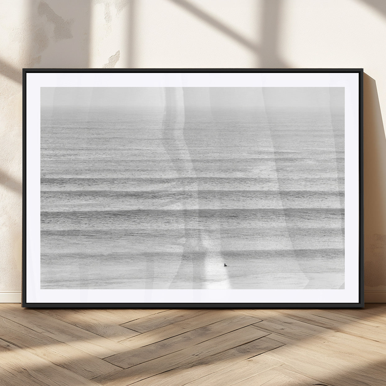 Monochrome photo of a lone surfer in calm layered waves, perfect for minimalist coastal or moody ocean-inspired wall decoration.