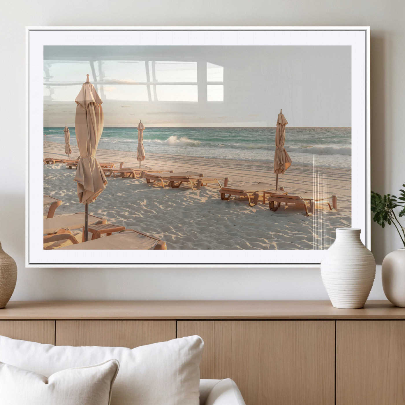 Minimalist photo of empty beach loungers and umbrellas on soft sand, ideal for calm seaside or pastel coastal-style home decor.
