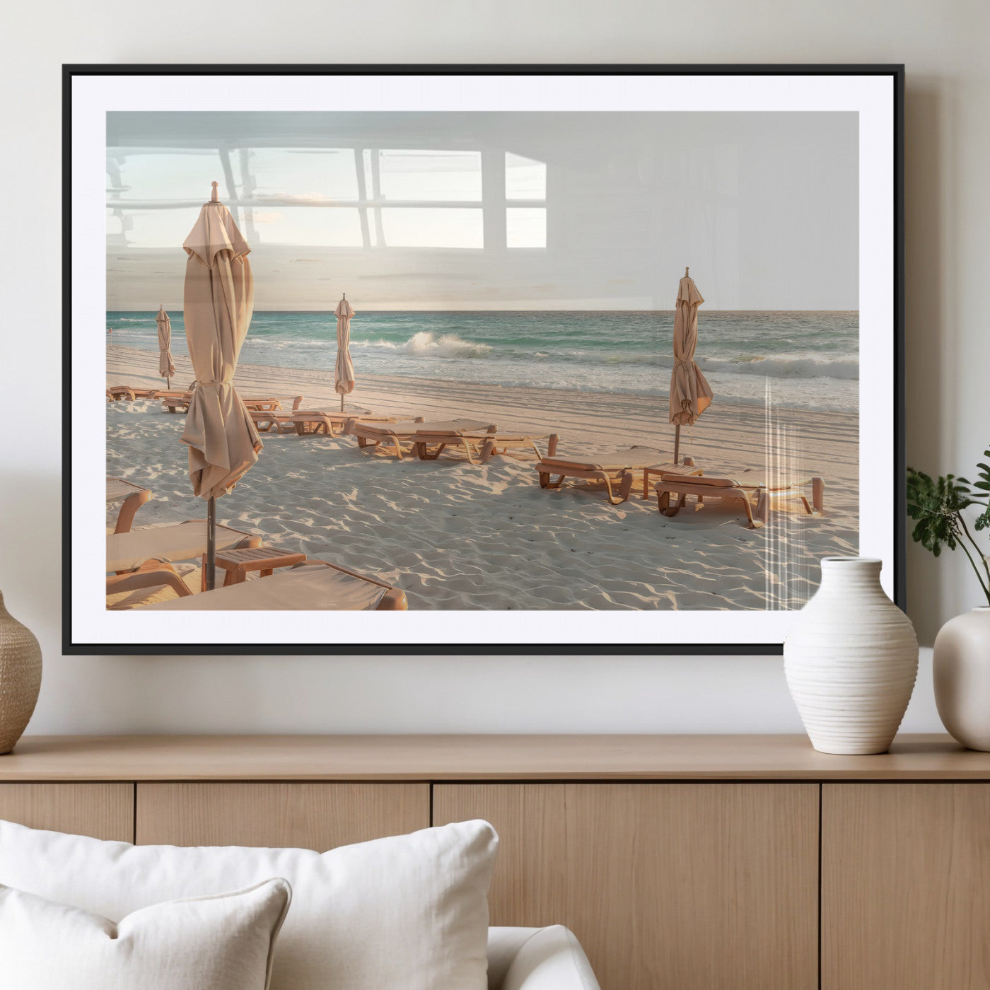 Minimalist photo of empty beach loungers and umbrellas on soft sand, ideal for calm seaside or pastel coastal-style home decor.