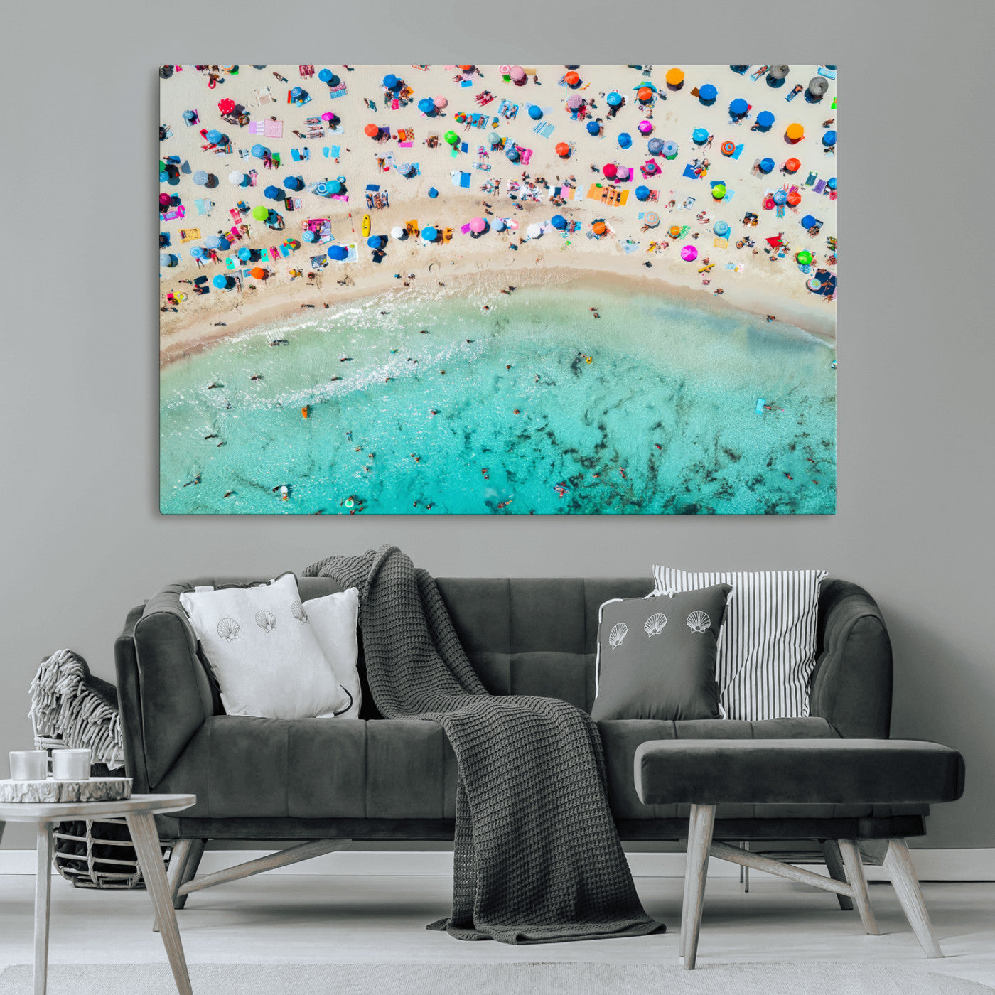 Aerial view of a vibrant beach filled with colorful umbrellas and people enjoying the turquoise ocean, capturing a lively summer vacation scene.