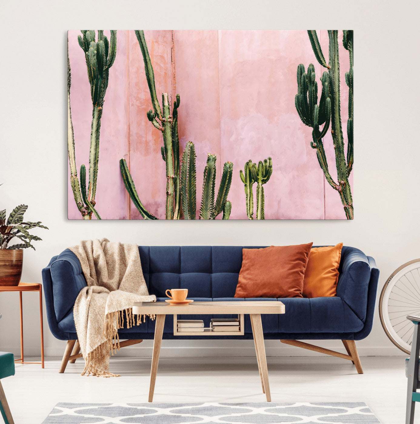 Framed canvas of tall green cacti against a soft pink wall, ideal for modern desert or colorful southwest-inspired home decor.