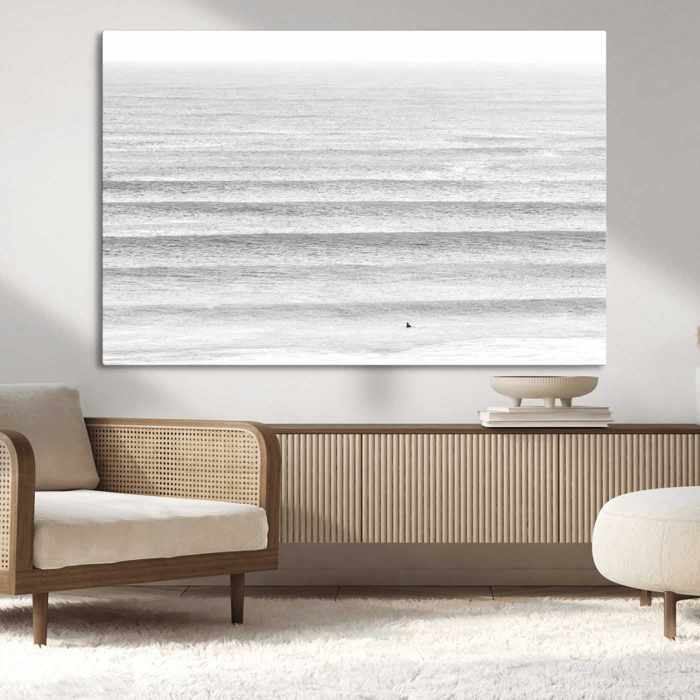Monochrome photo of a lone surfer in calm layered waves, perfect for minimalist coastal or moody ocean-inspired wall decoration.