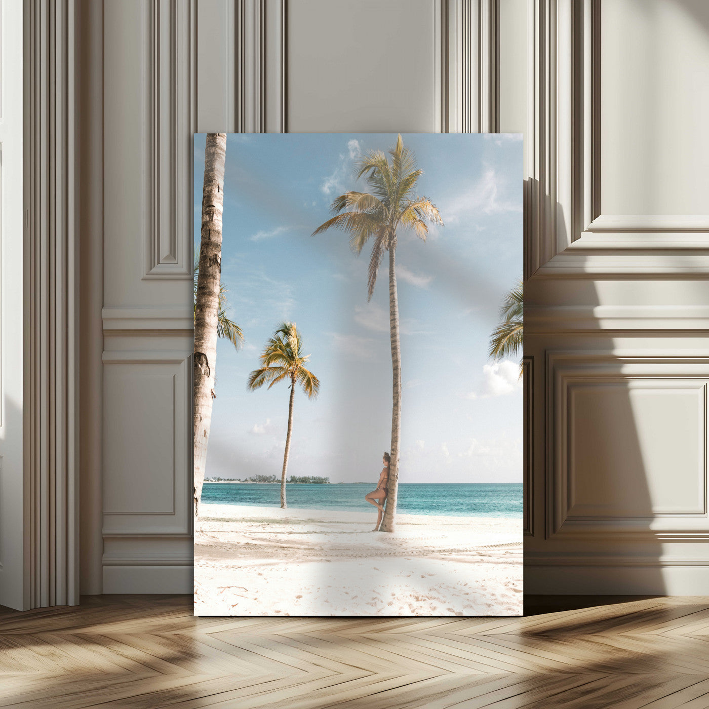 Person leaning on a palm tree at a tropical beach with white sand and turquoise water, perfect for coastal or beach-themed home decor.