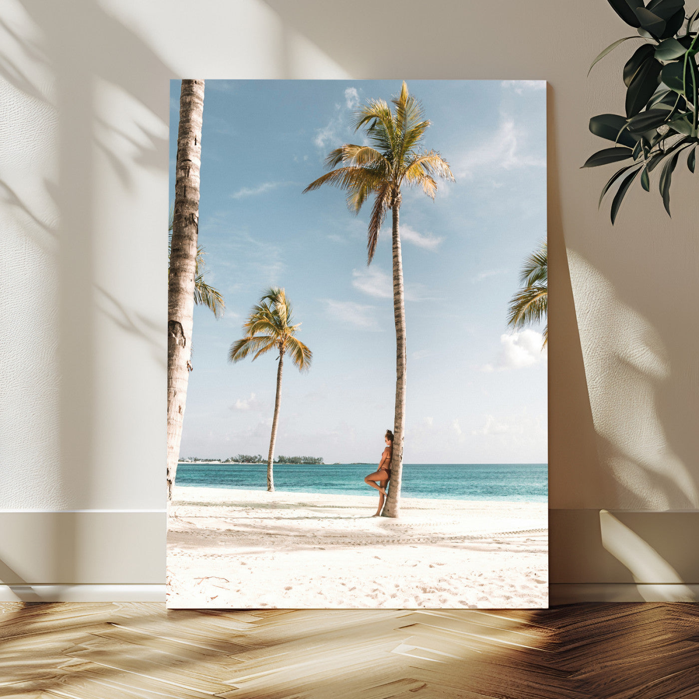 Person leaning on a palm tree at a tropical beach with white sand and turquoise water, perfect for coastal or beach-themed home decor.