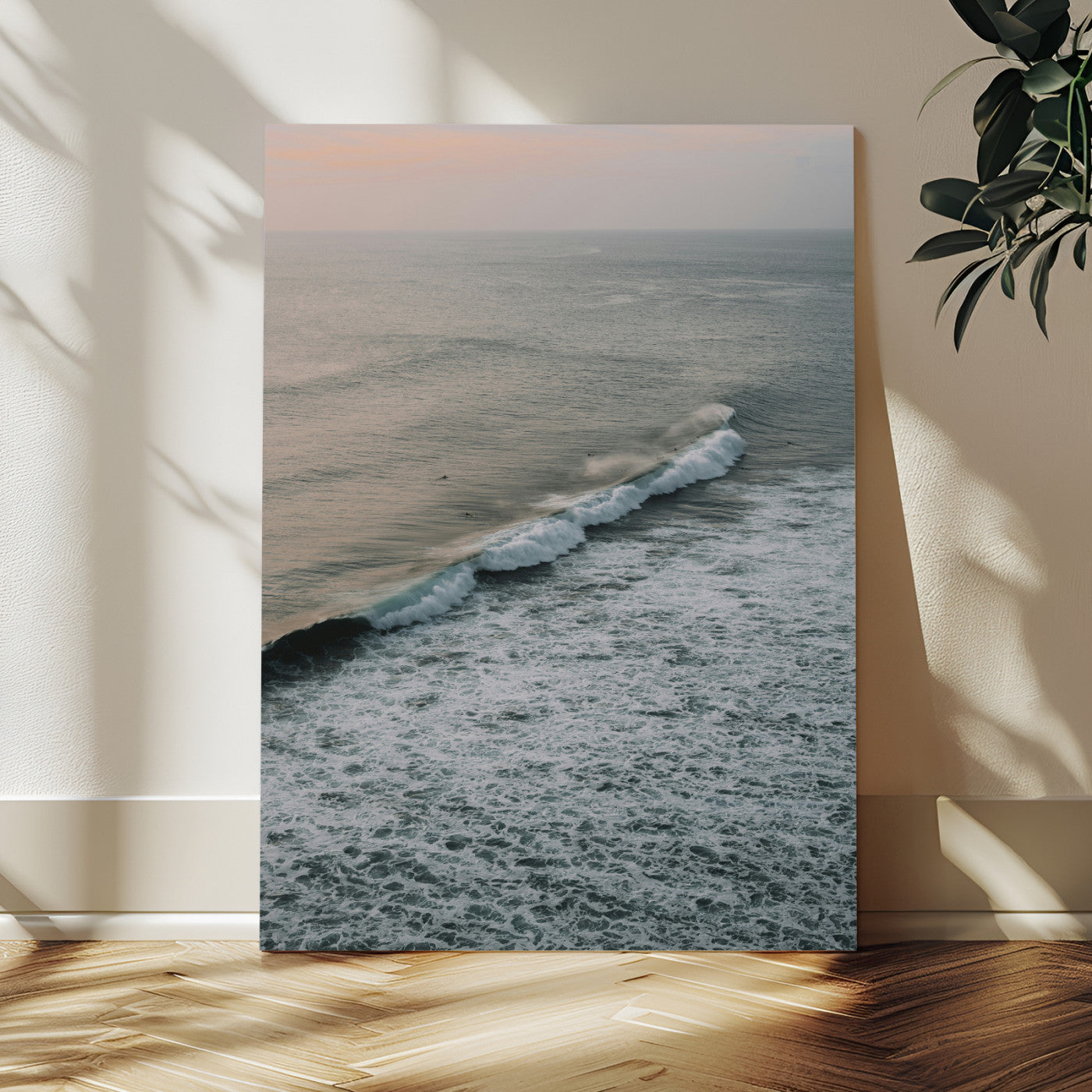 Aerial view of ocean waves rolling towards the shore under a soft sunset sky, creating a peaceful and minimalist coastal scene.