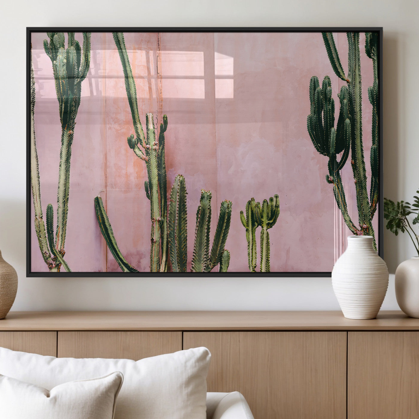 Framed canvas of tall green cacti against a soft pink wall, ideal for modern desert or colorful southwest-inspired home decor.