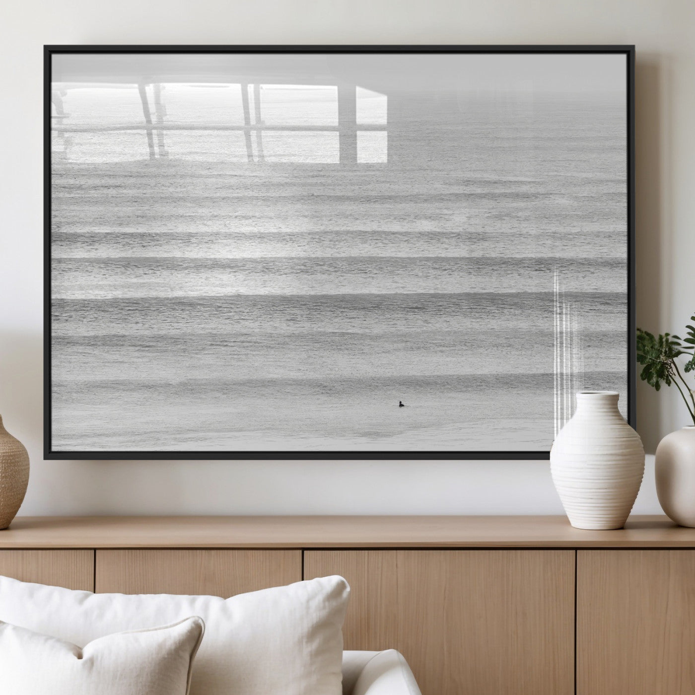 Monochrome photo of a lone surfer in calm layered waves, perfect for minimalist coastal or moody ocean-inspired wall decoration.