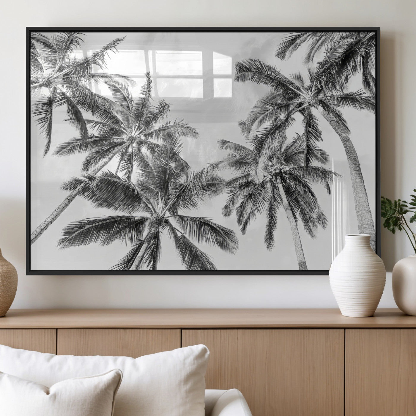 Black and white tropical palm trees viewed from below, swaying gently against a bright sky, creating a serene and elegant coastal atmosphere.