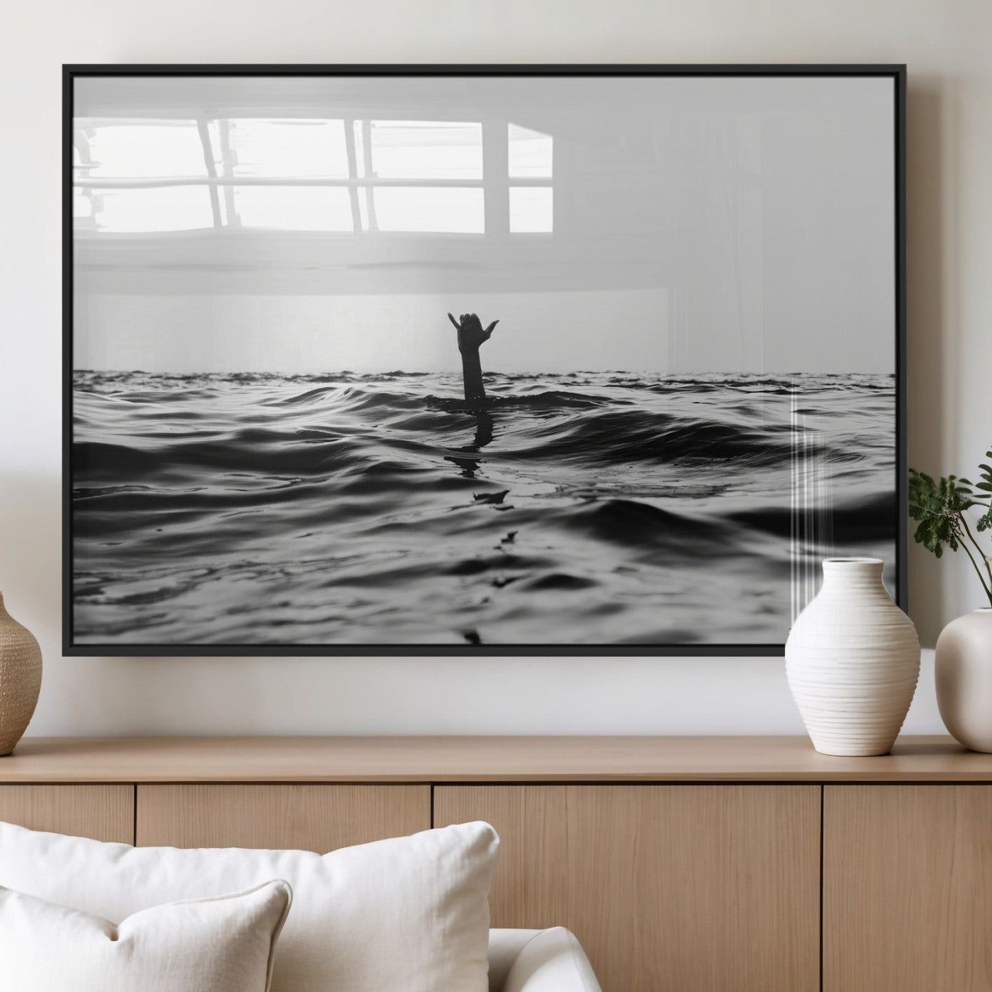 Black and white ocean with a hand making a surfer sign among dark waves, creating a dramatic and minimalist seascape with bold contrast.