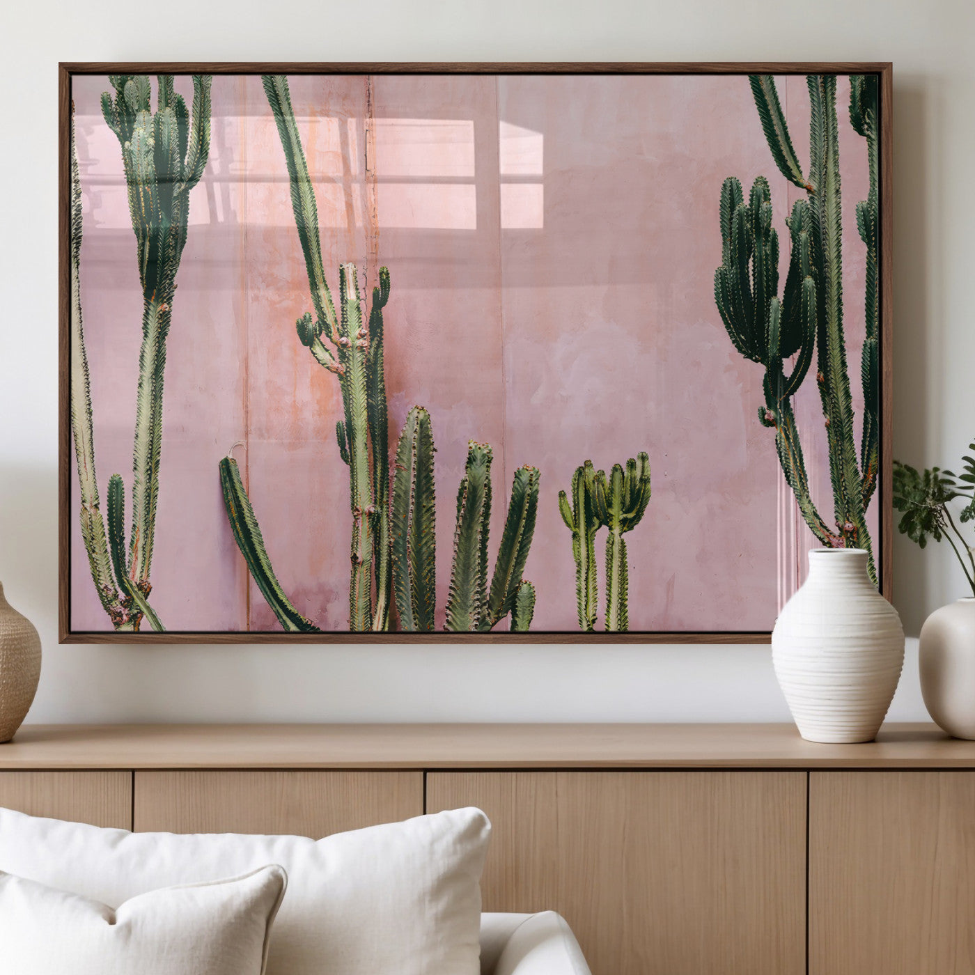 Framed canvas of tall green cacti against a soft pink wall, ideal for modern desert or colorful southwest-inspired home decor.