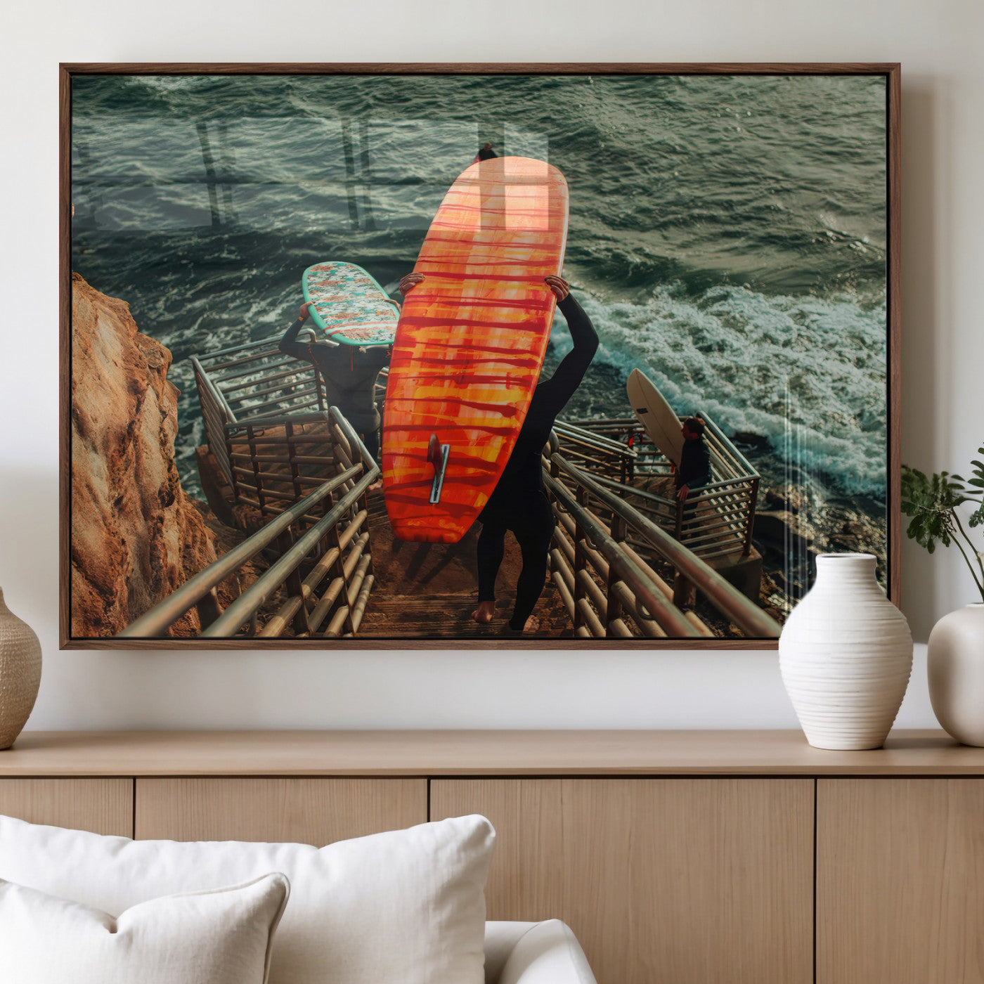 A surfer carrying a bold orange surfboard down a rugged staircase toward the ocean, bathed in golden hour light, capturing the energy of coastal adventure.