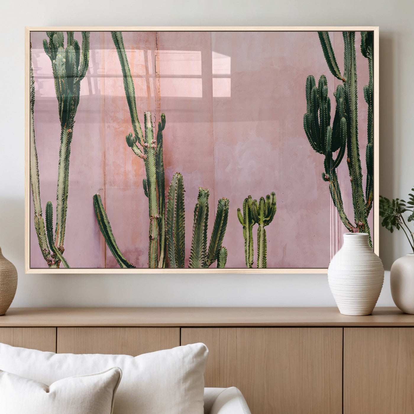 Framed canvas of tall green cacti against a soft pink wall, ideal for modern desert or colorful southwest-inspired home decor.