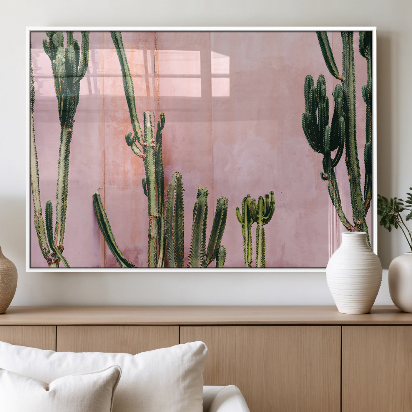 Framed canvas of tall green cacti against a soft pink wall, ideal for modern desert or colorful southwest-inspired home decor.