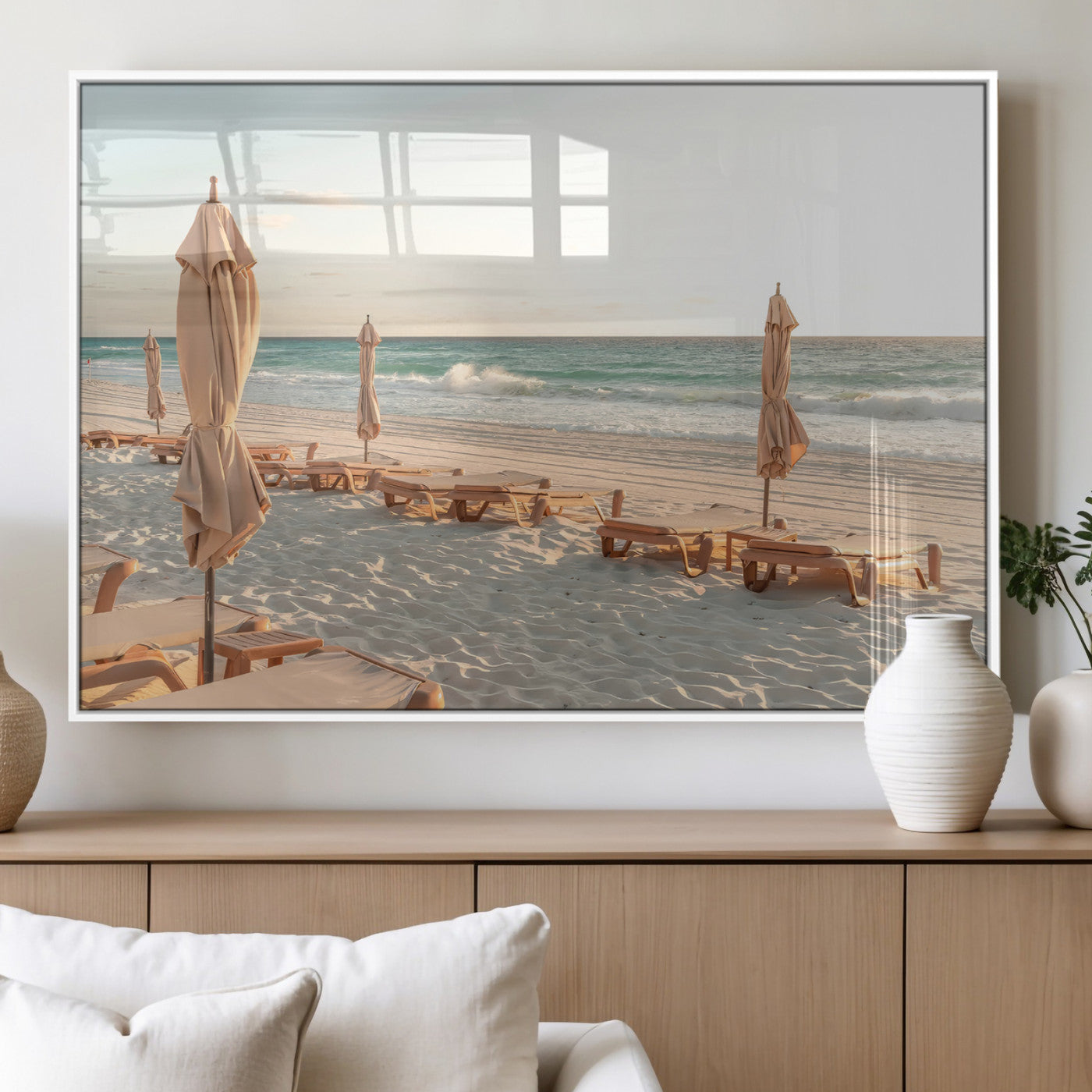 Minimalist photo of empty beach loungers and umbrellas on soft sand, ideal for calm seaside or pastel coastal-style home decor.