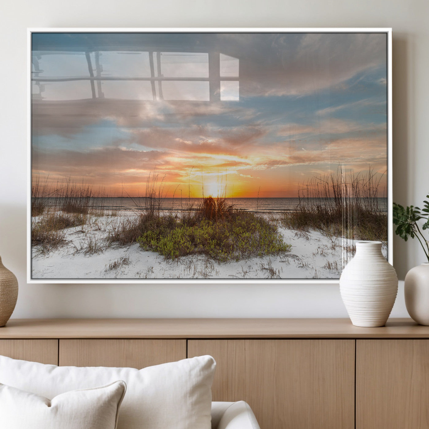 A tranquil beach scene featuring golden sunset hues over the water, with grasses in the foreground and a peaceful, serene atmosphere.