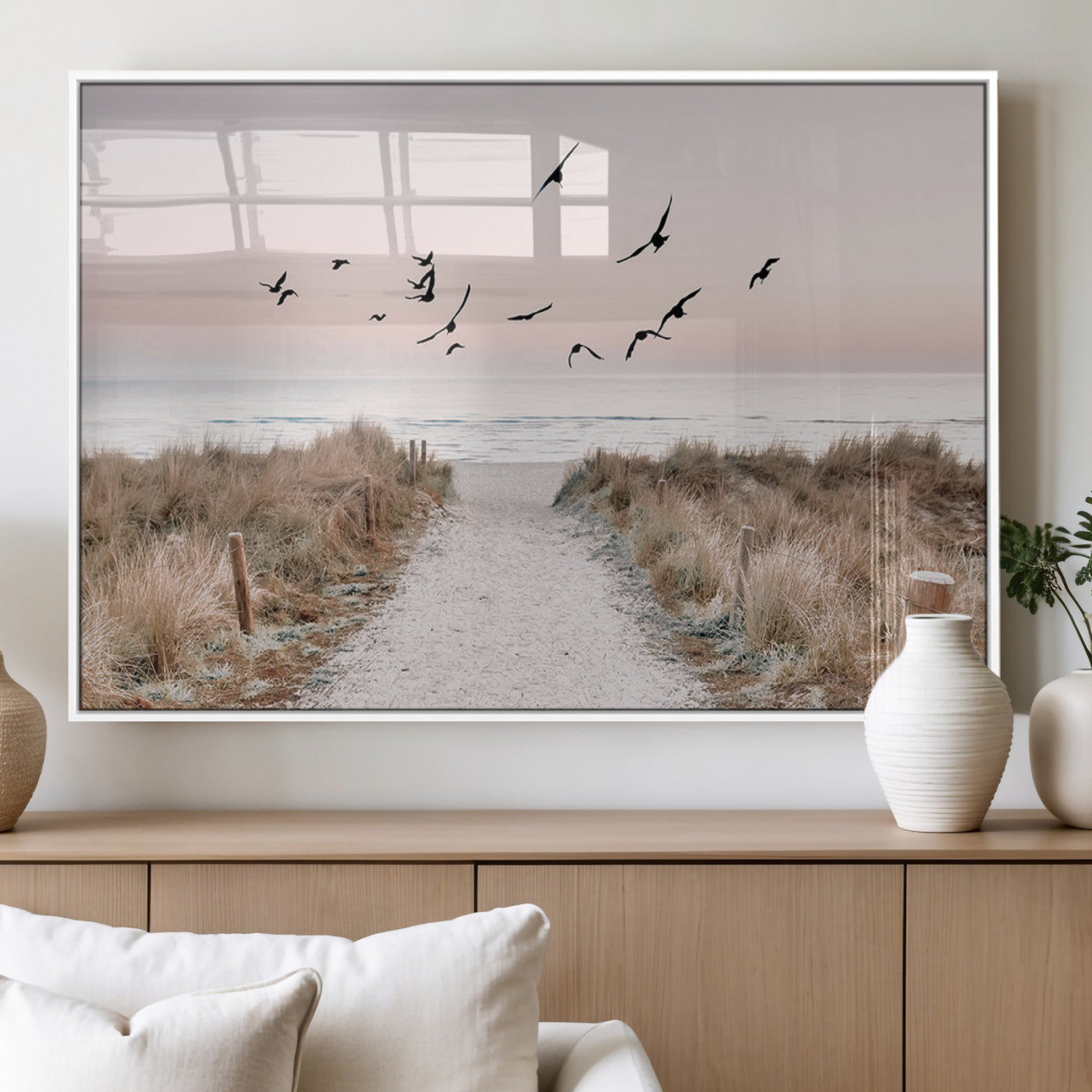 A peaceful coastal pathway leading to the ocean, with birds flying across a soft pastel sky, creating a calm and scenic beach atmosphere.