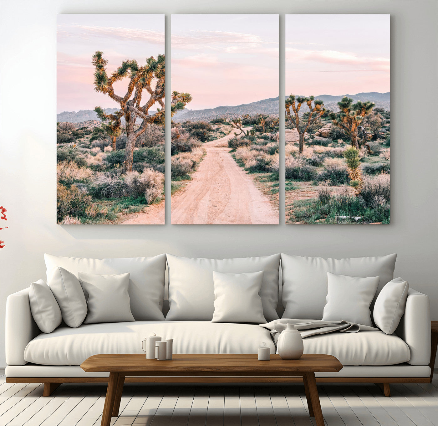 A dusty road winding through Joshua Tree National Park, framed by iconic twisted trees and warm desert tones under a soft pastel sky.