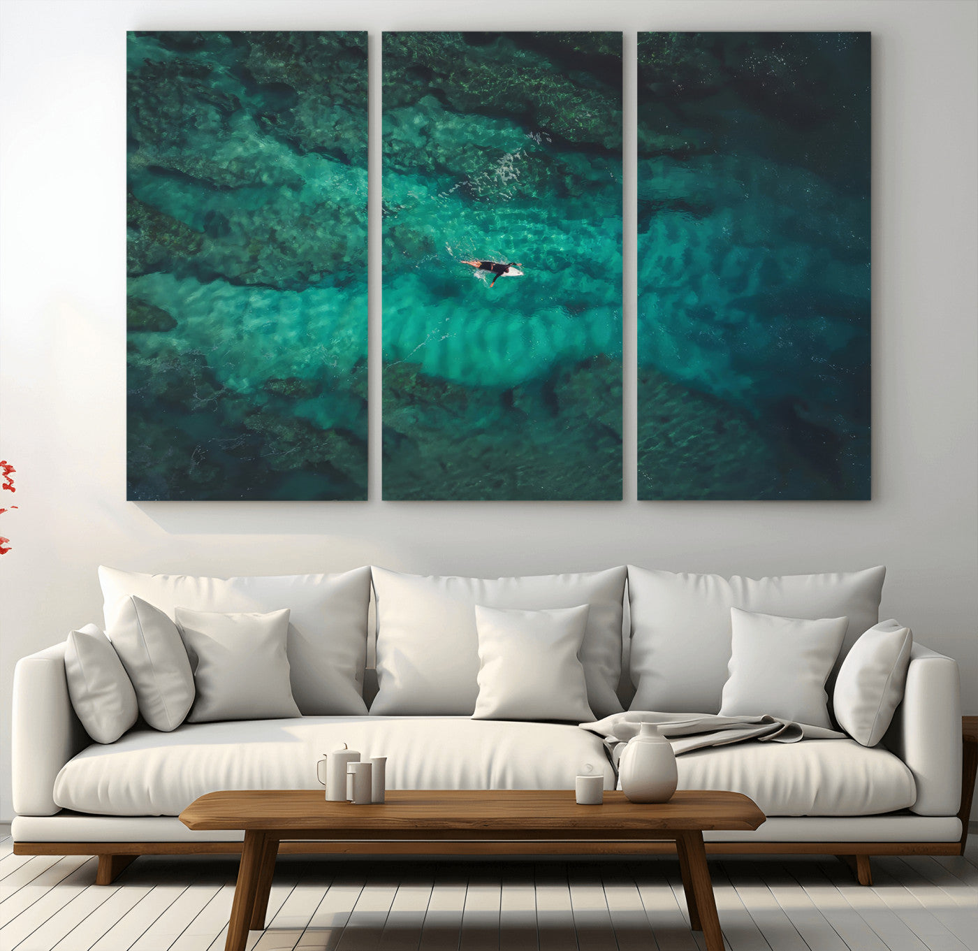 An aerial view of a solo surfer paddling through crystal-clear turquoise waters over a sunlit reef, capturing the beauty and serenity of open water surfing.
