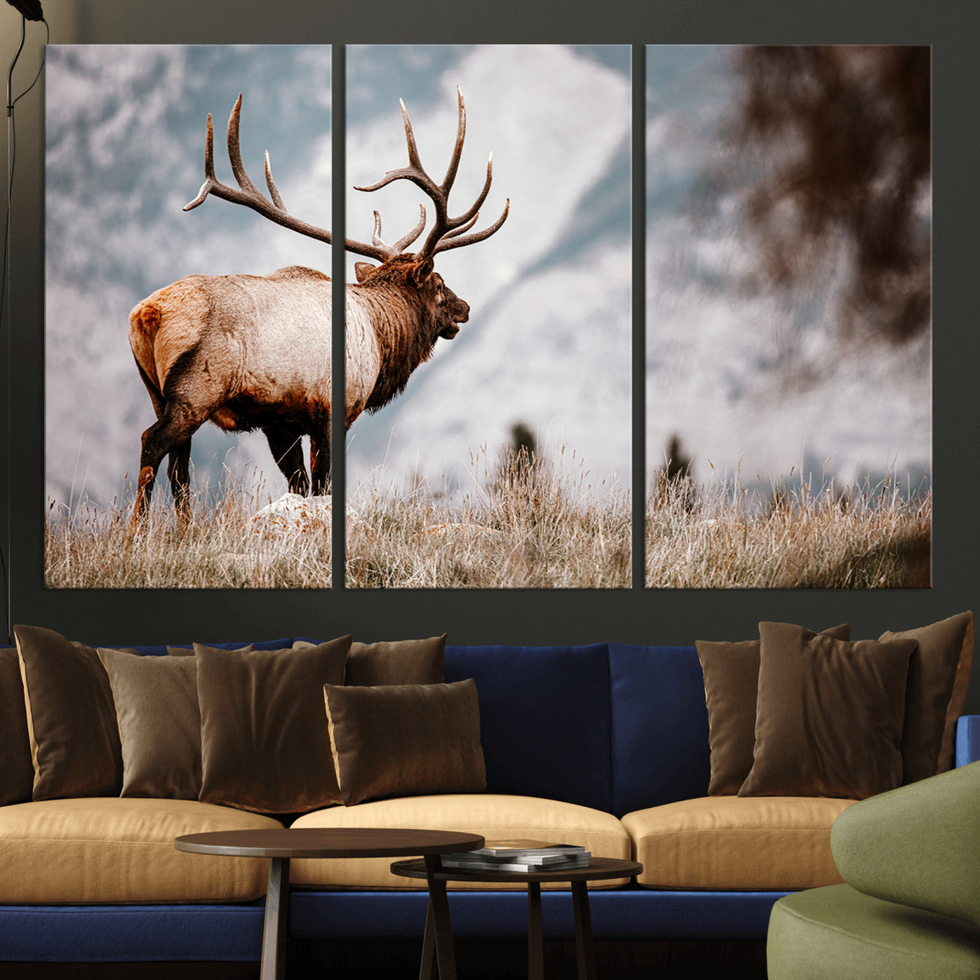 Majestic elk with large antlers standing in grass with snowy mountains in background, perfect for rustic cabin or lodge style decor.