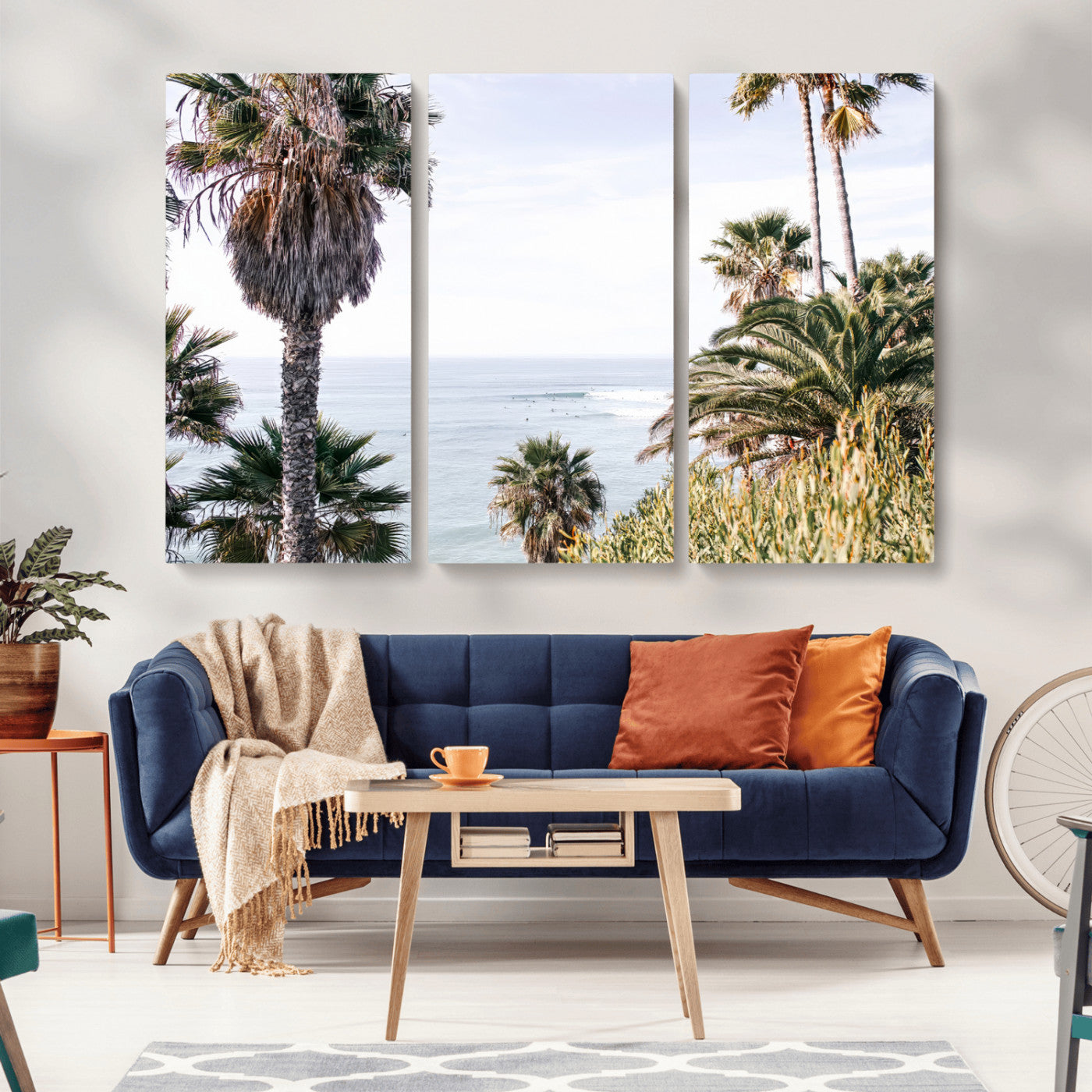 Scenic coastal view with tall palm trees overlooking a calm ocean, soft blue waves, and surfers in the distance, creating a peaceful tropical vibe.