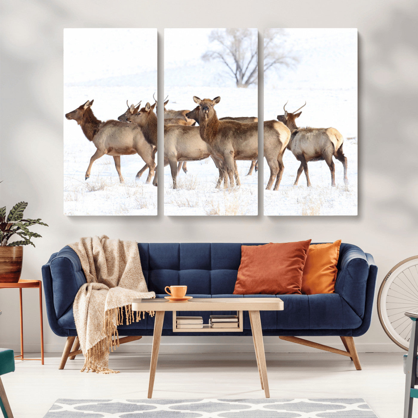 A group of elk standing on snowy terrain with a tree in the background, perfect for rustic or lodge-style winter wall decor.