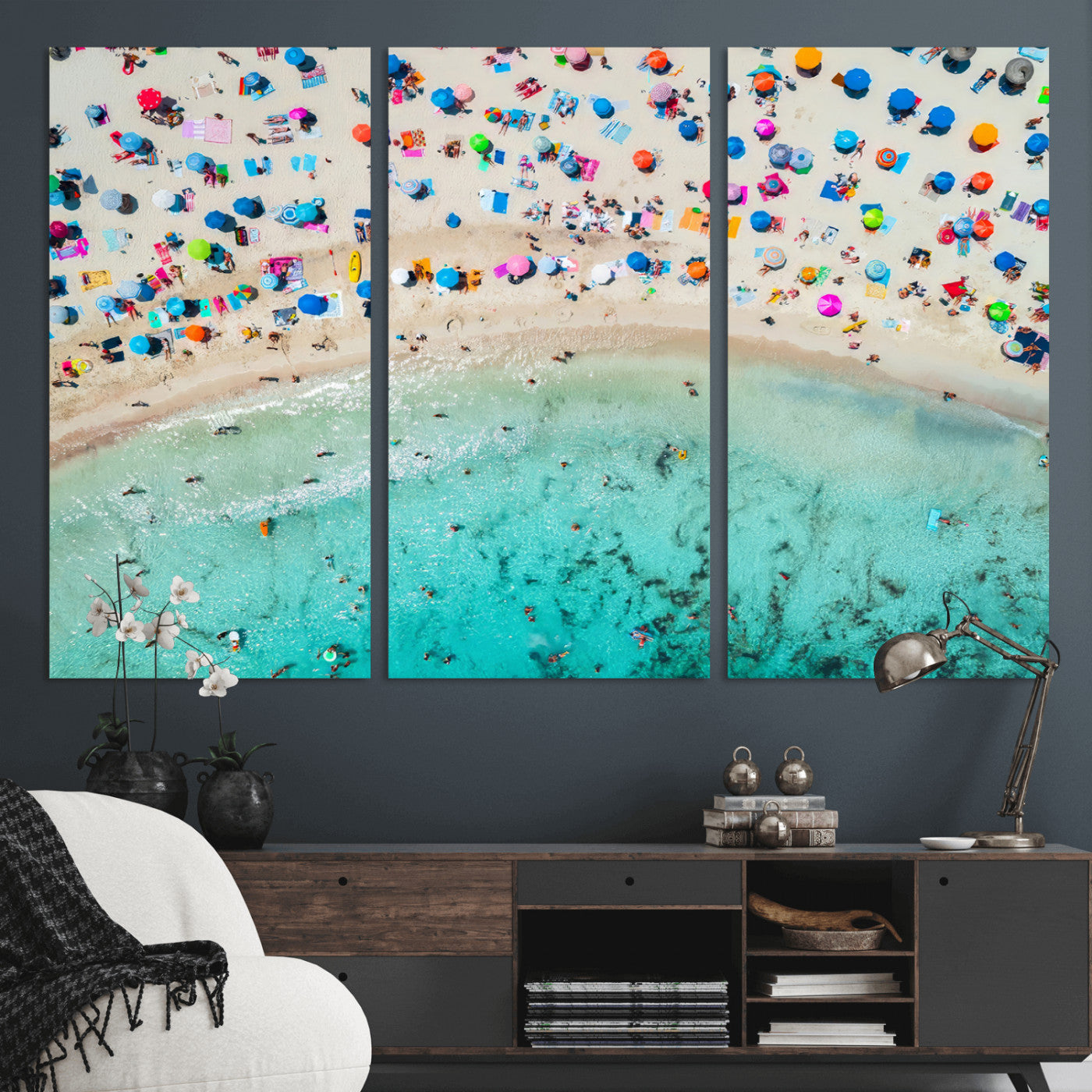 Aerial view of a vibrant beach filled with colorful umbrellas and people enjoying the turquoise ocean, capturing a lively summer vacation scene.