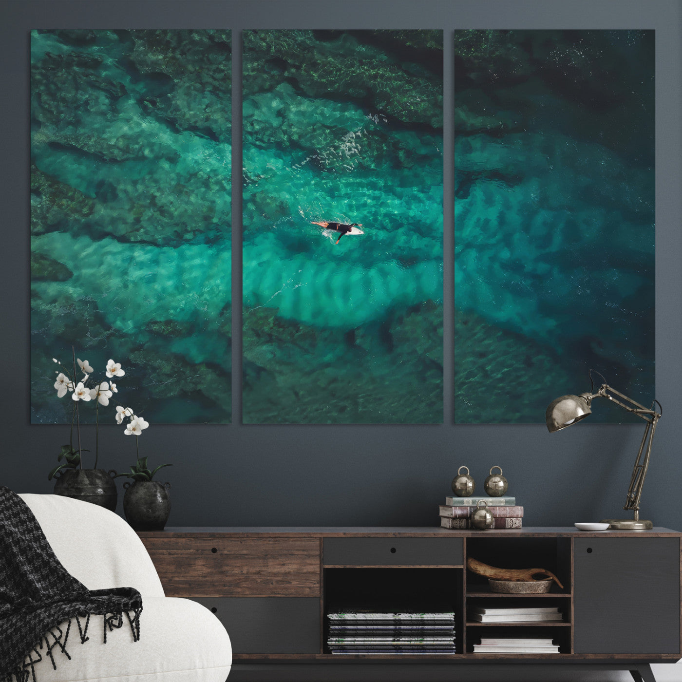 An aerial view of a solo surfer paddling through crystal-clear turquoise waters over a sunlit reef, capturing the beauty and serenity of open water surfing.