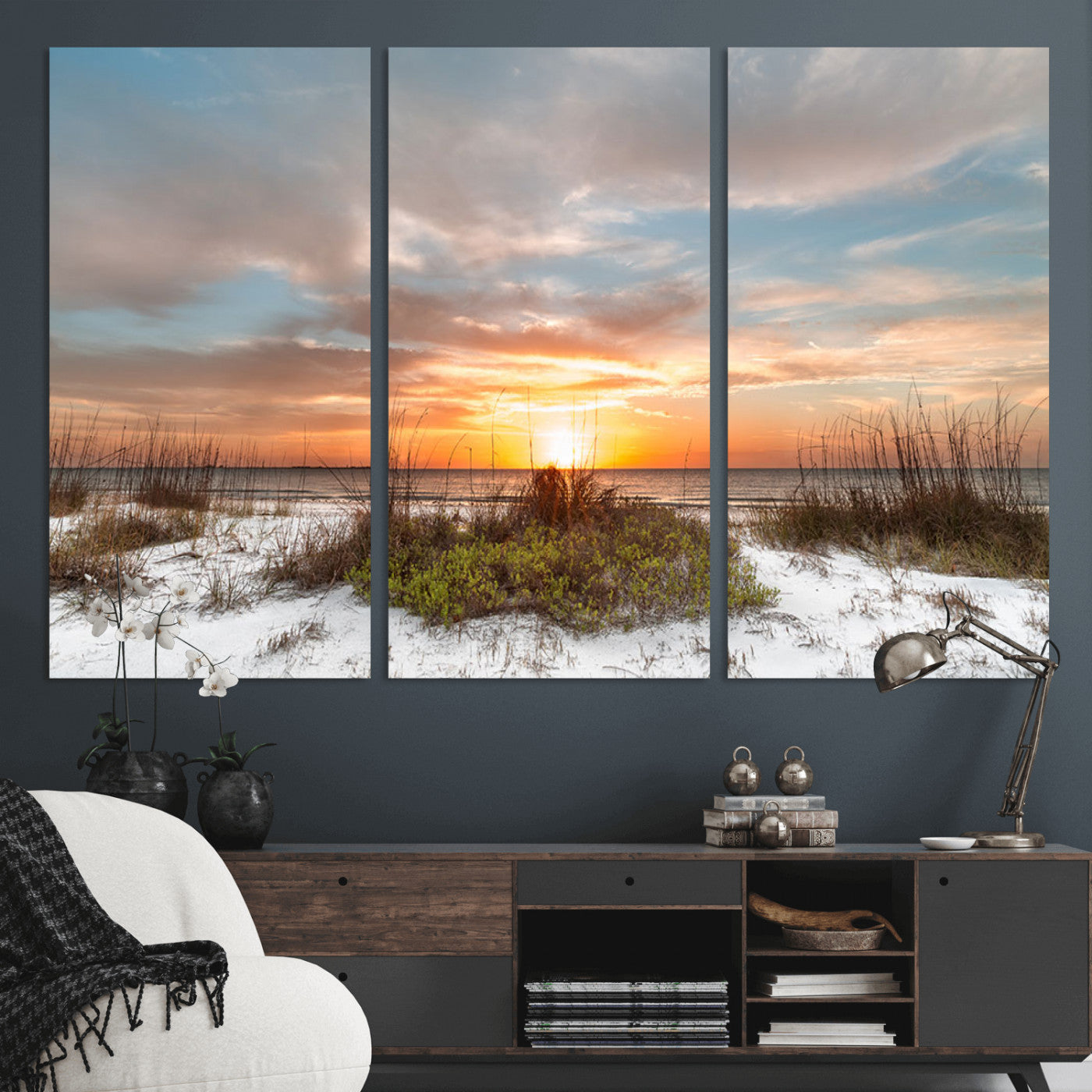 A tranquil beach scene featuring golden sunset hues over the water, with grasses in the foreground and a peaceful, serene atmosphere.
