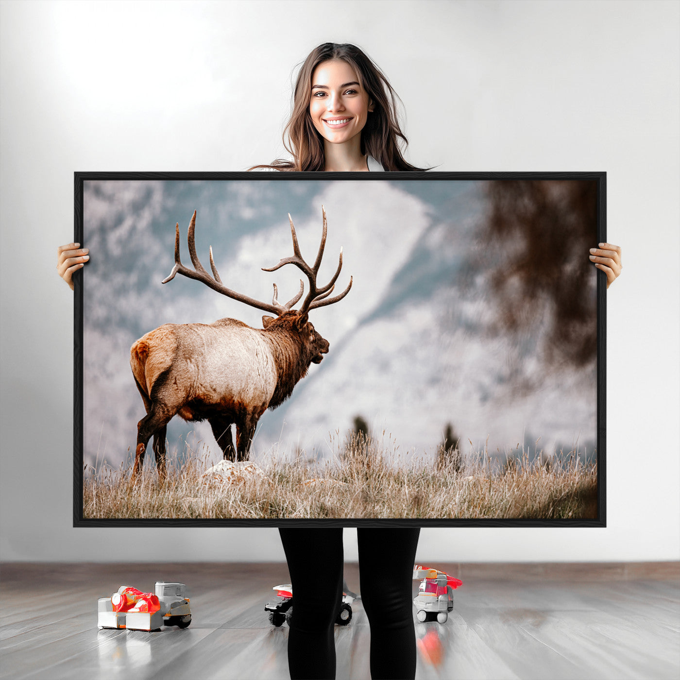 Majestic elk with large antlers standing in grass with snowy mountains in background, perfect for rustic cabin or lodge style decor.