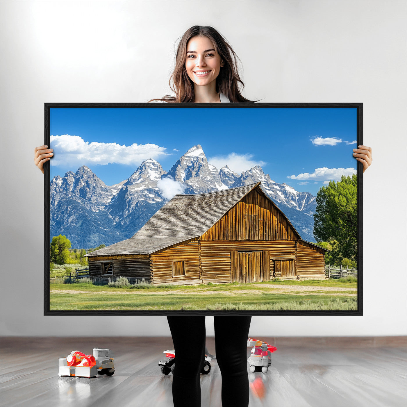 A rustic wooden barn sits in front of towering mountain peaks under a clear blue sky, perfect for farmhouse or cabin style interiors.