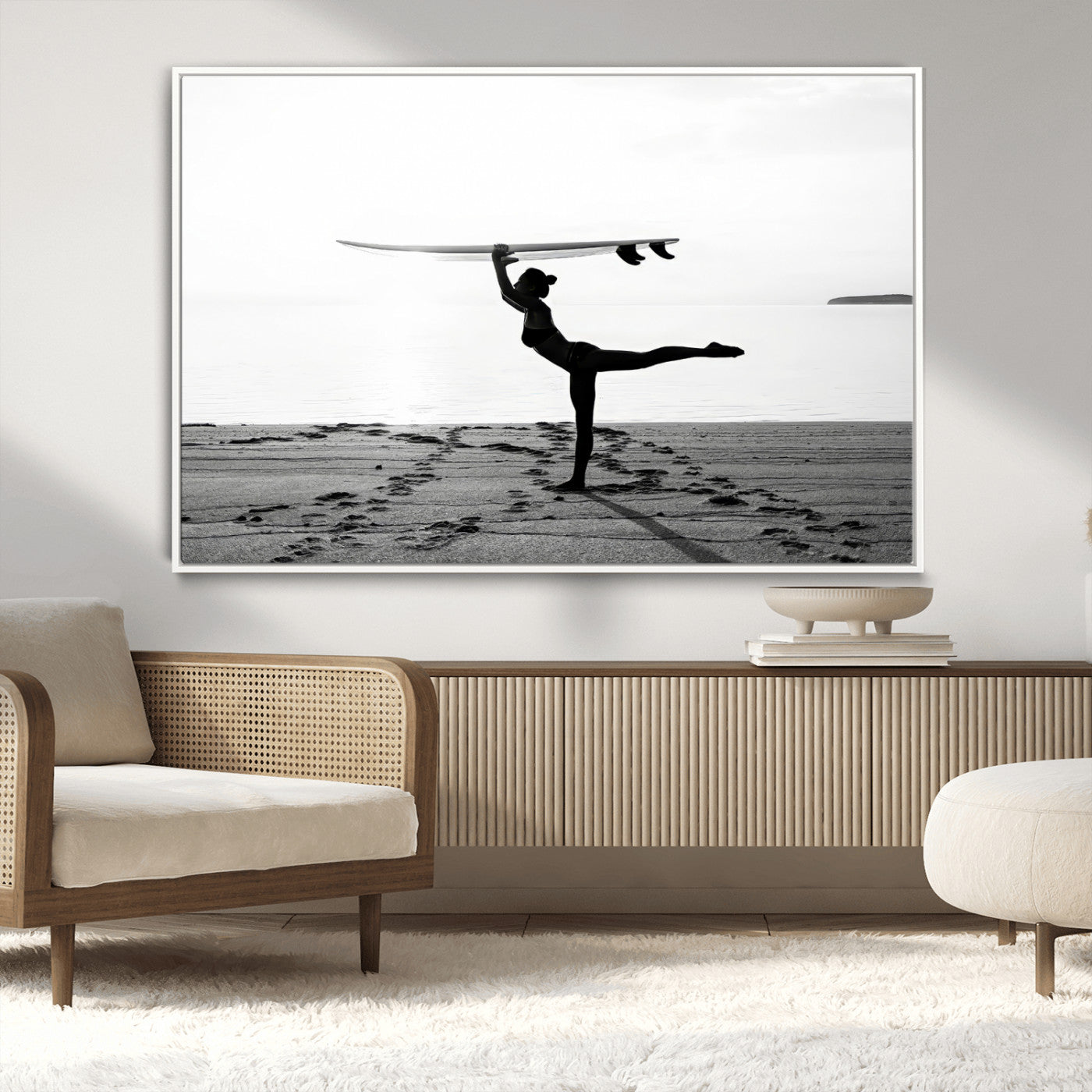 A woman balances a surfboard on her head while striking a yoga pose on the beach, silhouetted against a calm ocean horizon.
