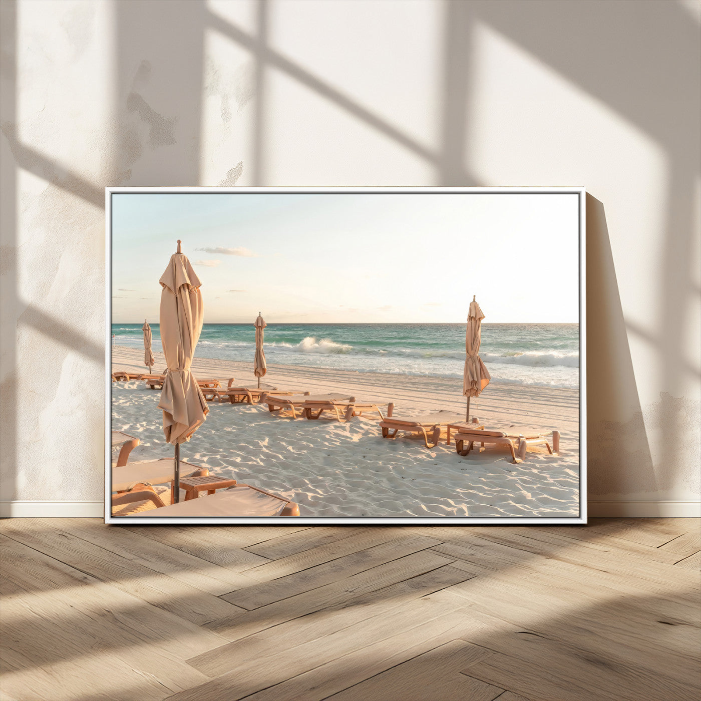 Minimalist photo of empty beach loungers and umbrellas on soft sand, ideal for calm seaside or pastel coastal-style home decor.