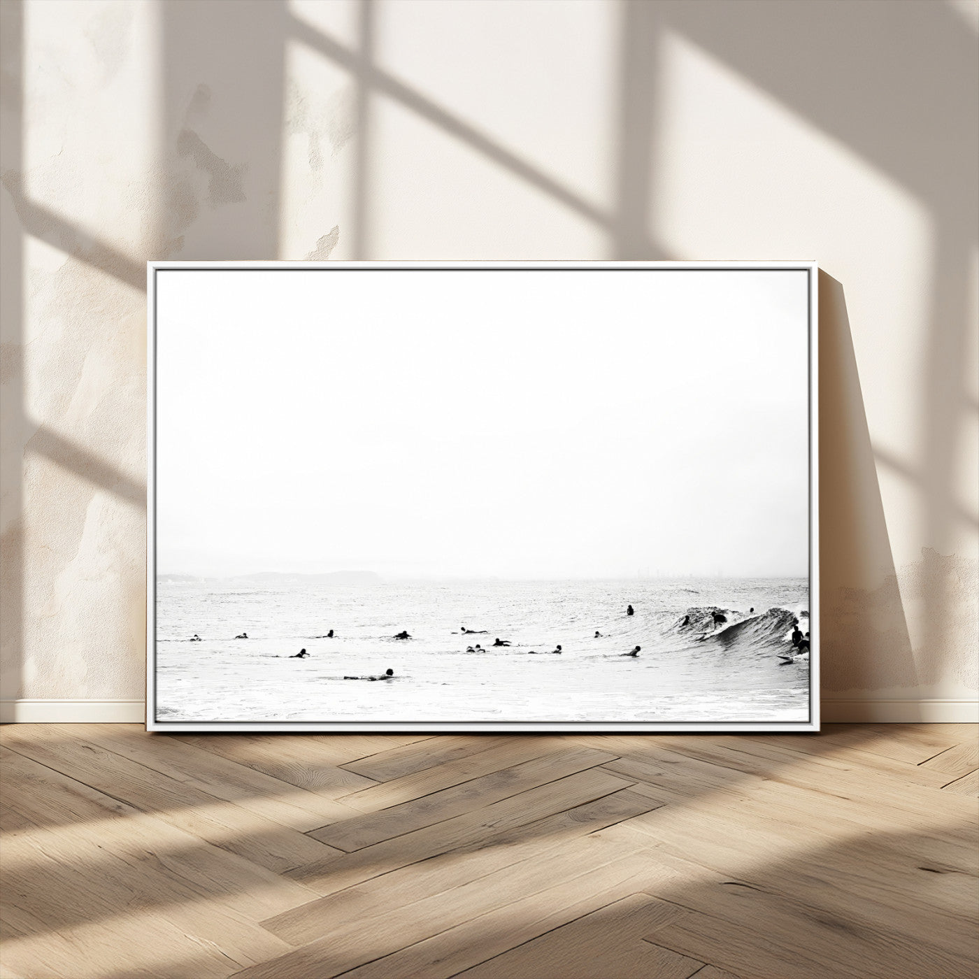 A group of surfers floating in the ocean, waiting for waves under a vast, moody sky, captured in black and white.