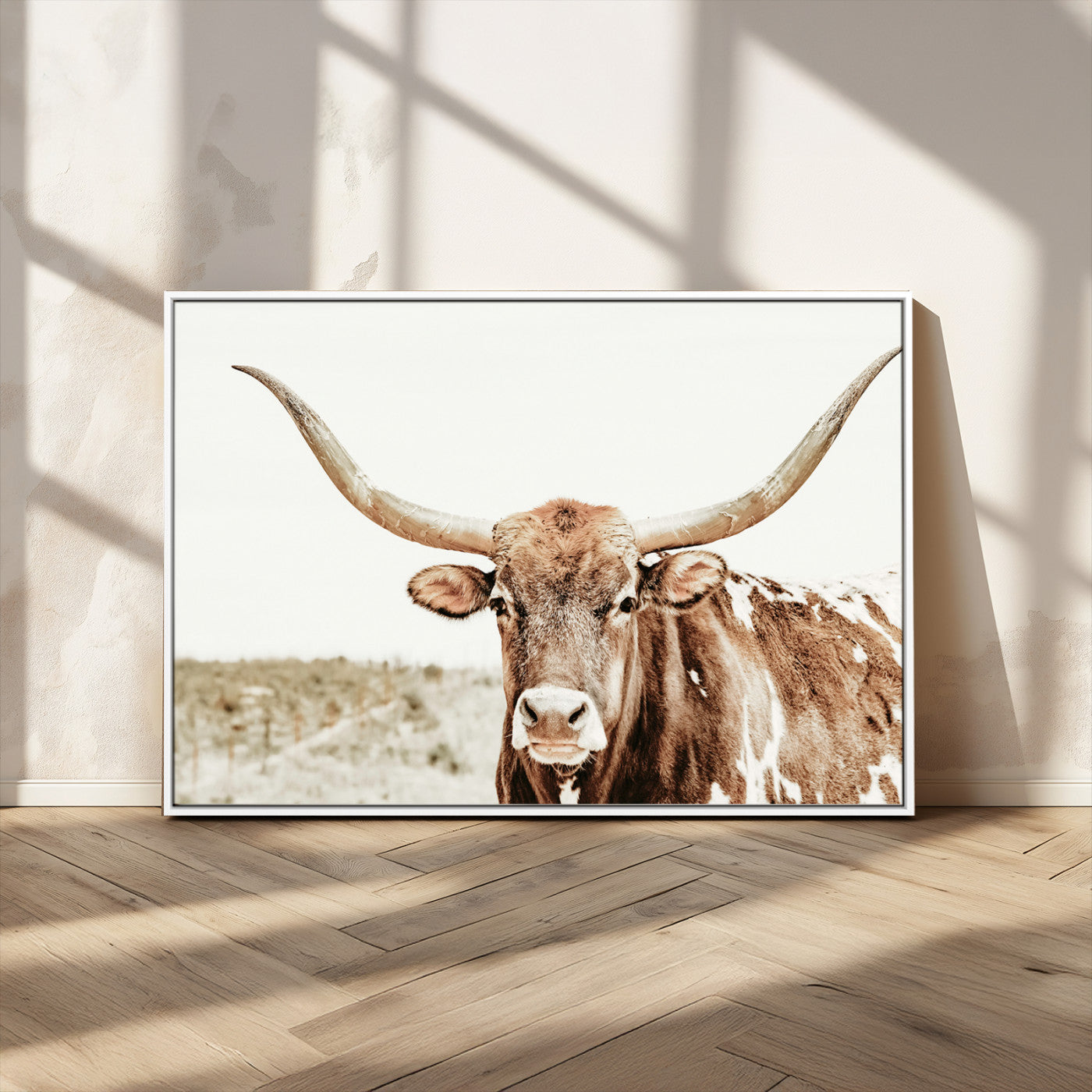A Texas longhorn bull with wide horns, standing in a dry field under soft light, ideal for rustic farmhouse or western-themed interiors.