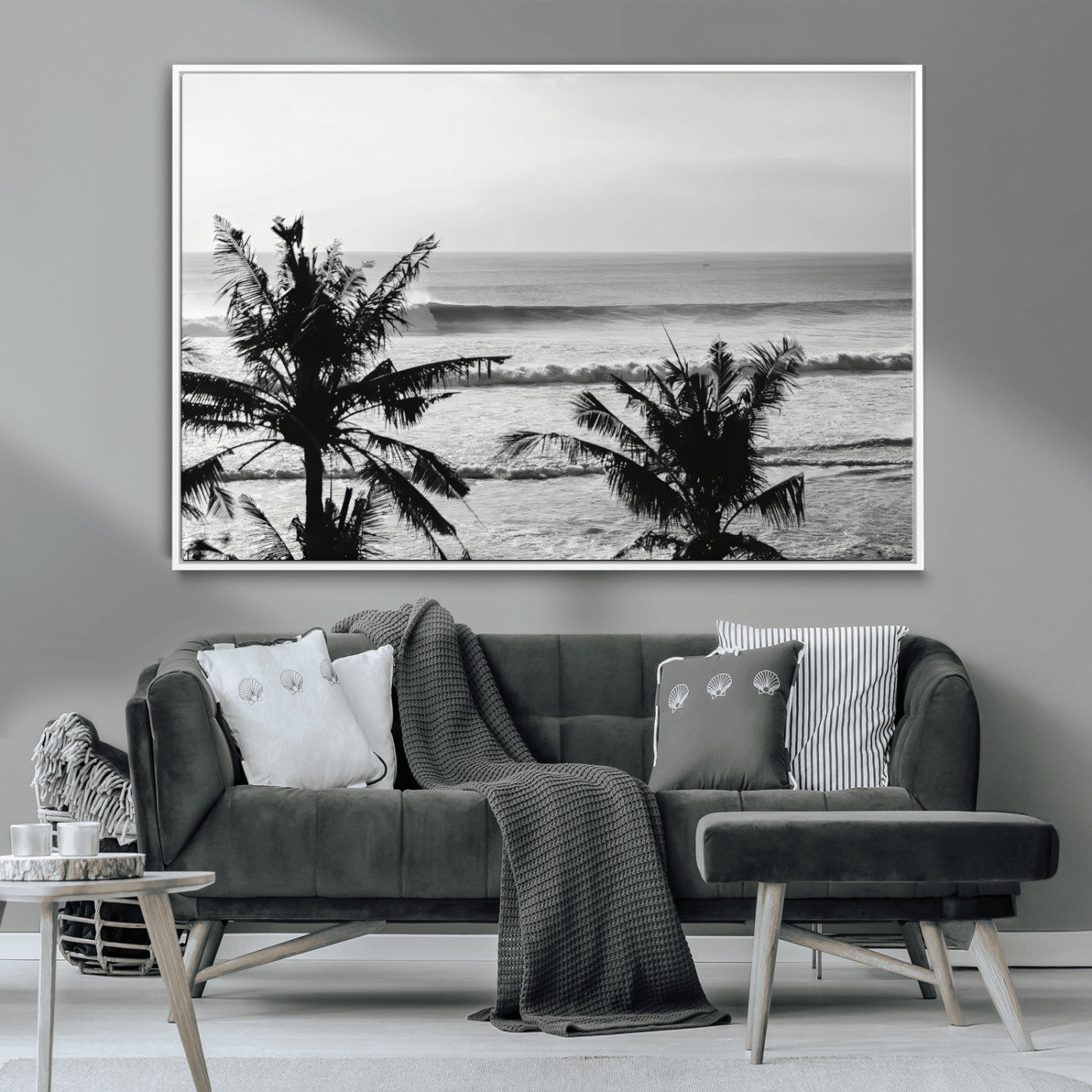 Black and white view of ocean waves crashing on a tropical coastline, framed by silhouetted palm trees under a vast, open sky.