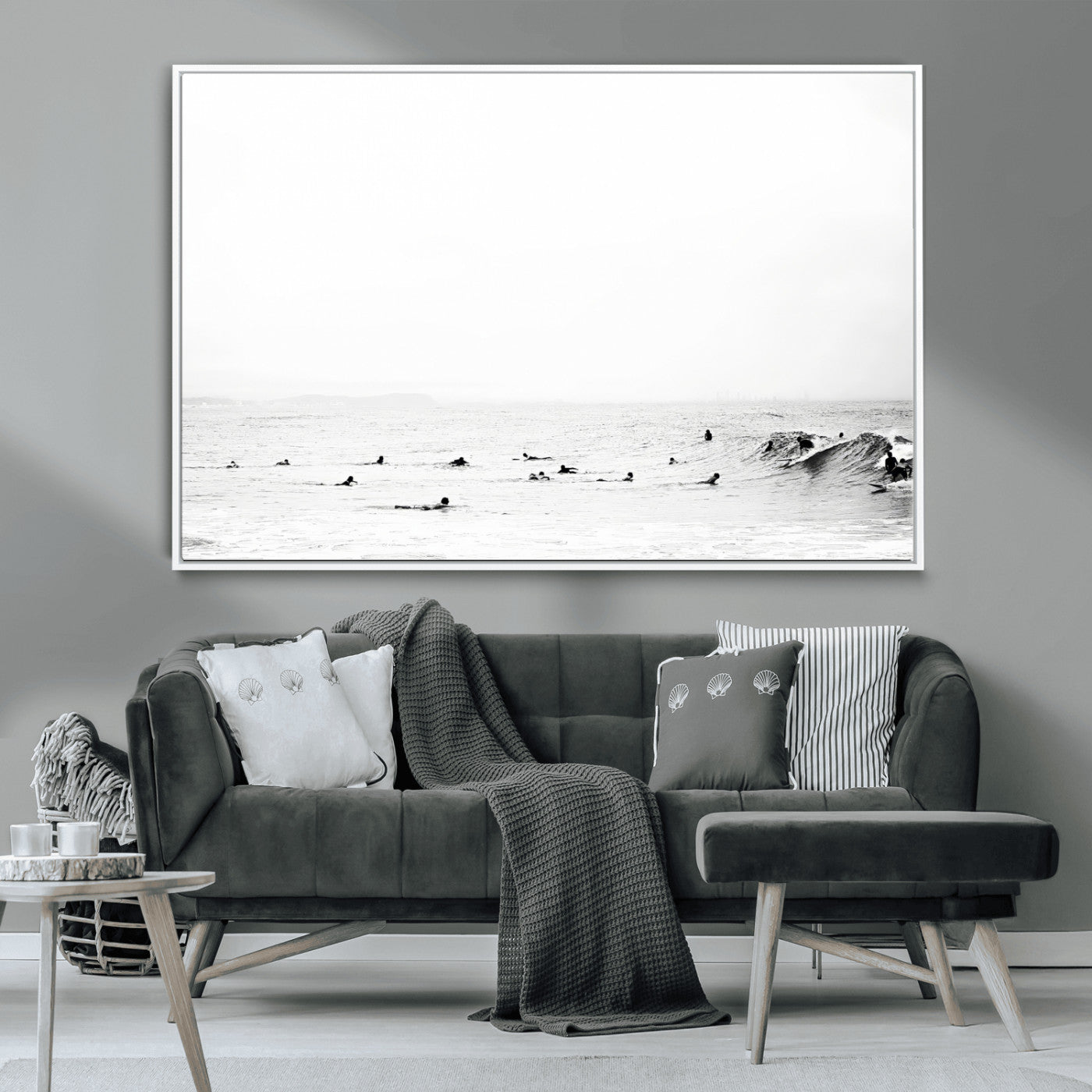 A group of surfers floating in the ocean, waiting for waves under a vast, moody sky, captured in black and white.