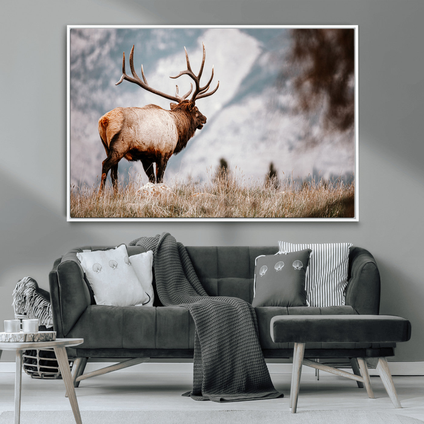 Majestic elk with large antlers standing in grass with snowy mountains in background, perfect for rustic cabin or lodge style decor.