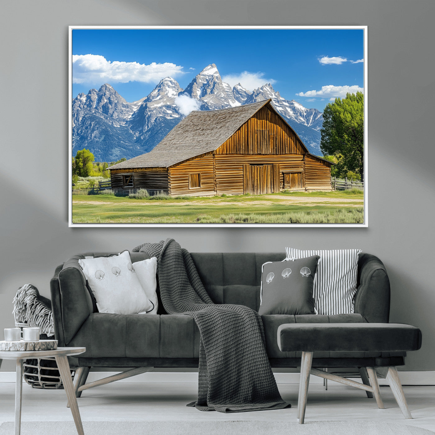 A rustic wooden barn sits in front of towering mountain peaks under a clear blue sky, perfect for farmhouse or cabin style interiors.