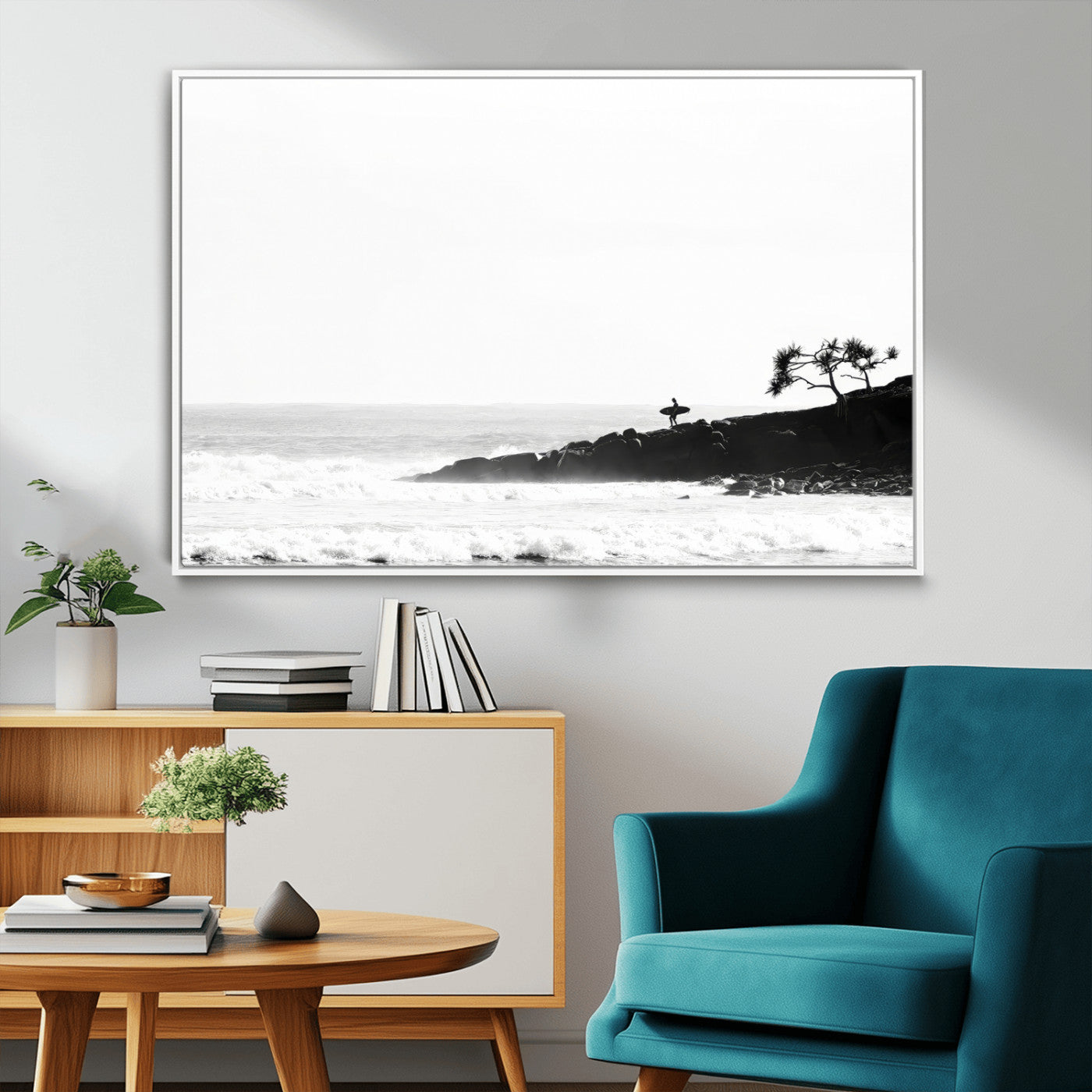 Black and white photo of a surfer standing on rocky cliffs, gazing at the waves, embodying the spirit of adventure and solitude.