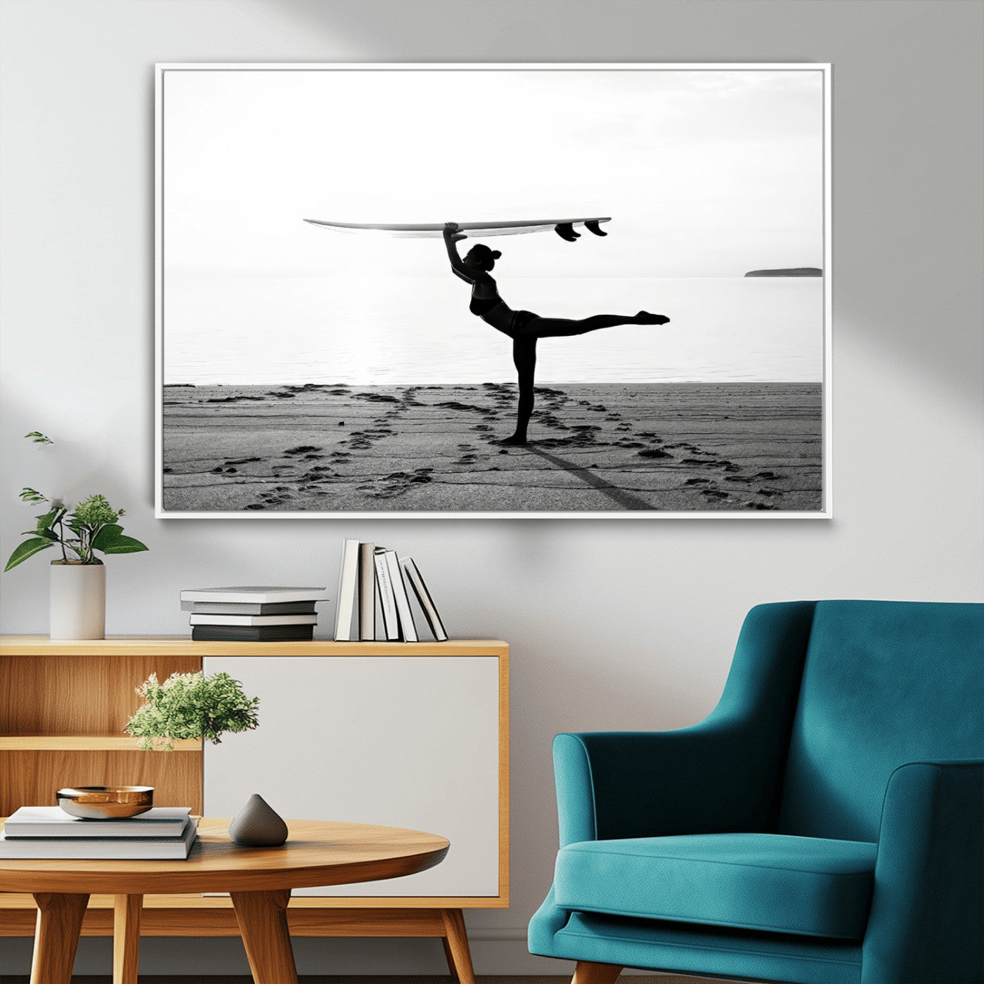 A woman balances a surfboard on her head while striking a yoga pose on the beach, silhouetted against a calm ocean horizon.